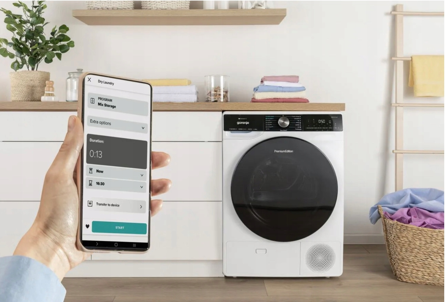 Smartfon steruje białą suszarką do ubrań. Na ekranie widać program suszenia.