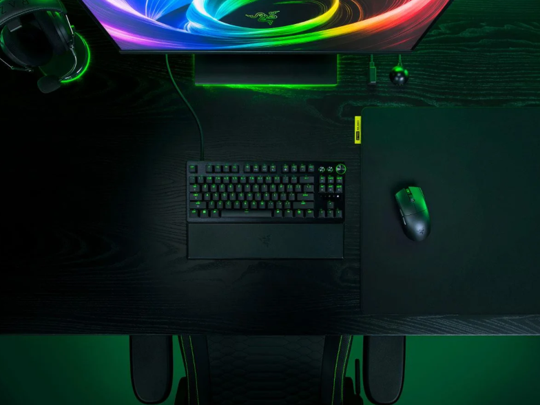 Zestaw do gier z podświetlaną na zielono klawiaturą, myszą, słuchawkami i monitorem.