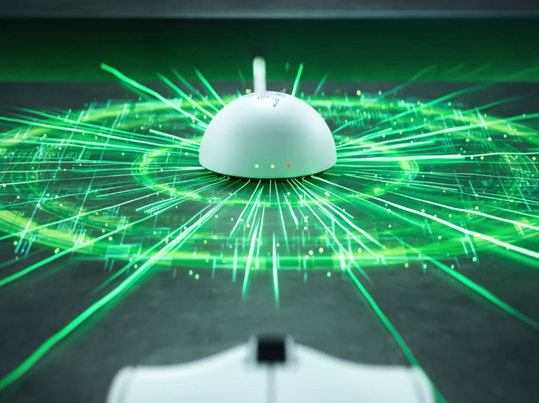 Białe urządzenie emituje zielone snopy światła na ciemnej powierzchni.