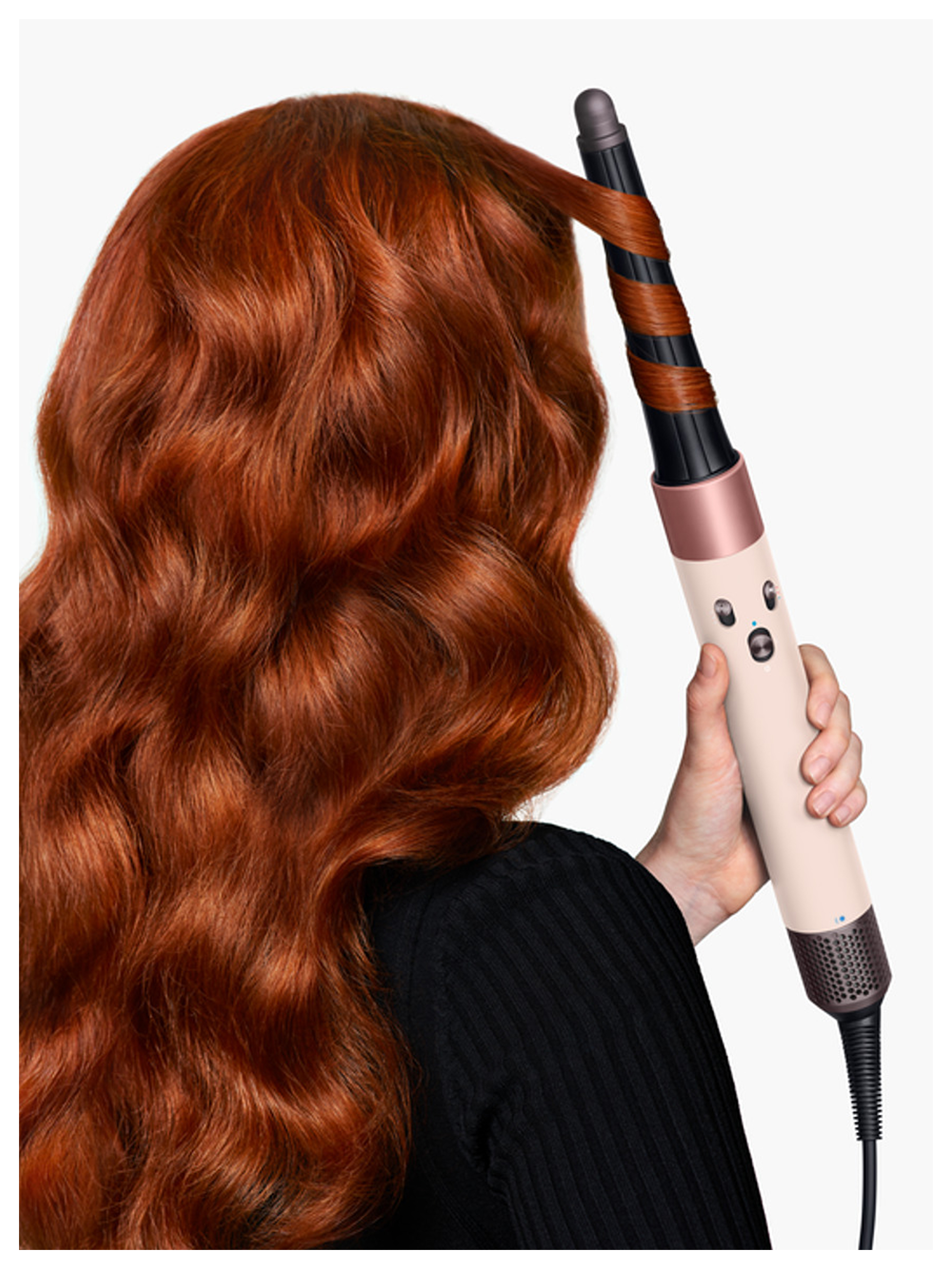 Kızıl saçlı bir kişi, rose gold detaylı saç maşası kullanıyor.