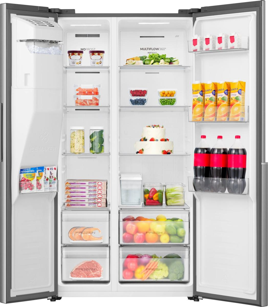 Otwarta lodówka z kostkarką, lodem, mrożonkami, sokiem pomarańczowym, colą i owocami.