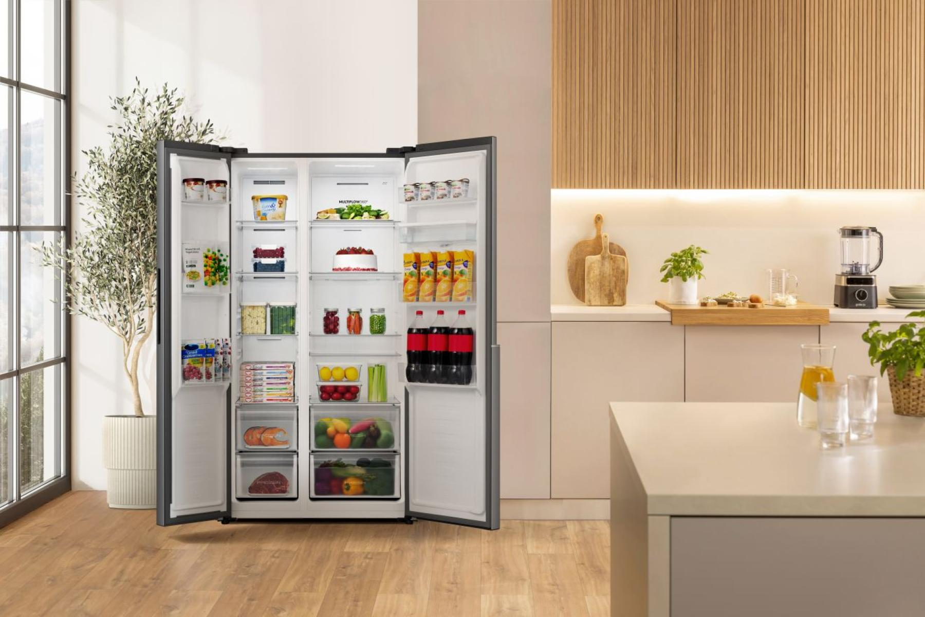 Otwarta lodówka wypełniona jedzeniem, obok kuchni.