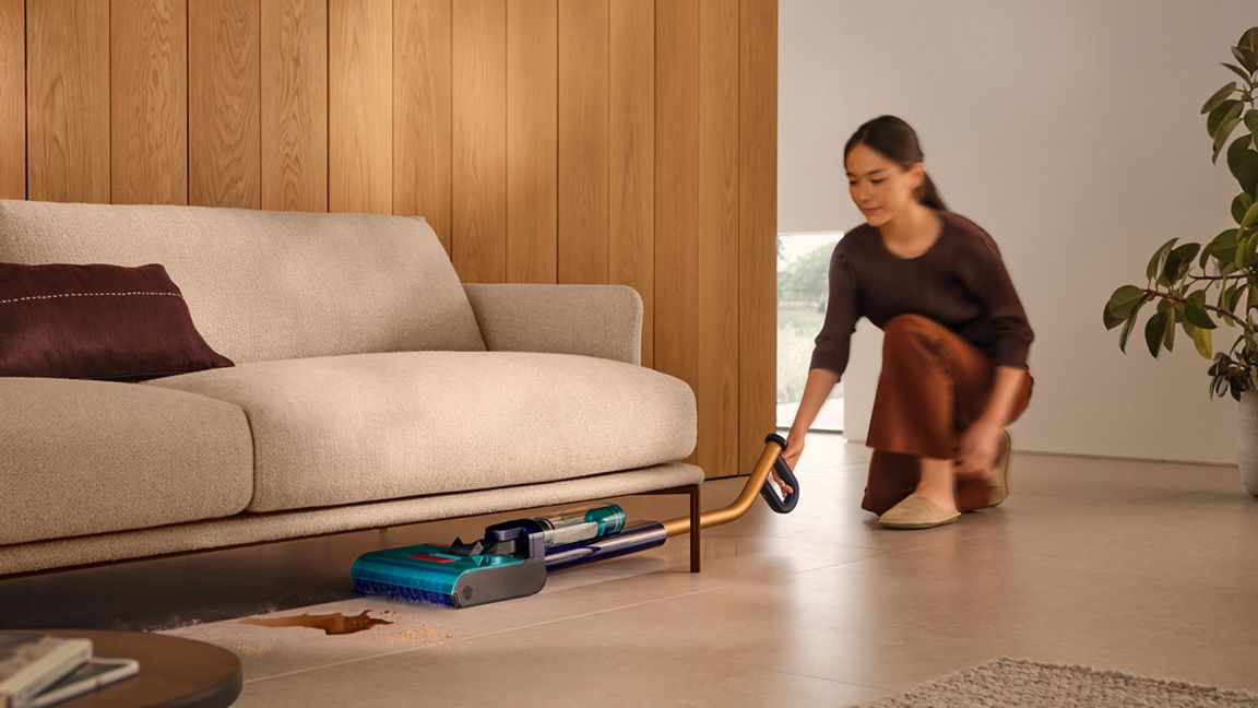 Une femme passe l'aspirateur sous un canapé. Un aspirateur nettoie un déversement.