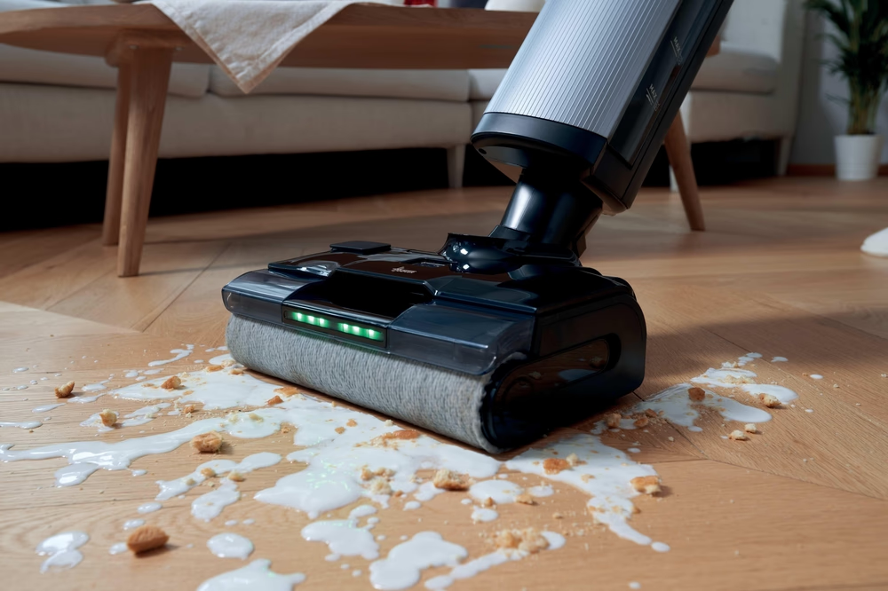 Bodenreiniger mit grünen LEDs reinigt verschüttete Flüssigkeit und Krümel auf Holzboden.
