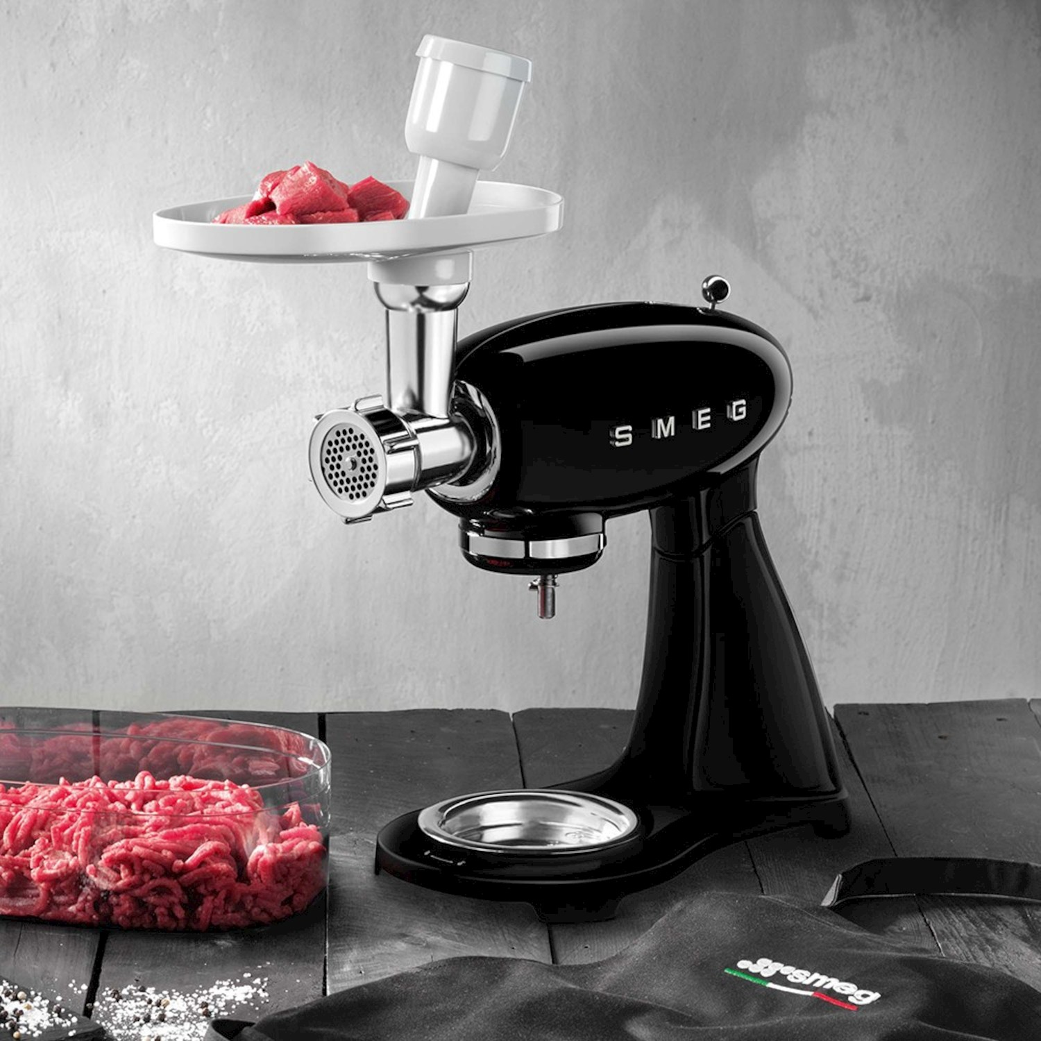 Un accessorio per tritacarne nero per un robot da cucina con carne cruda.