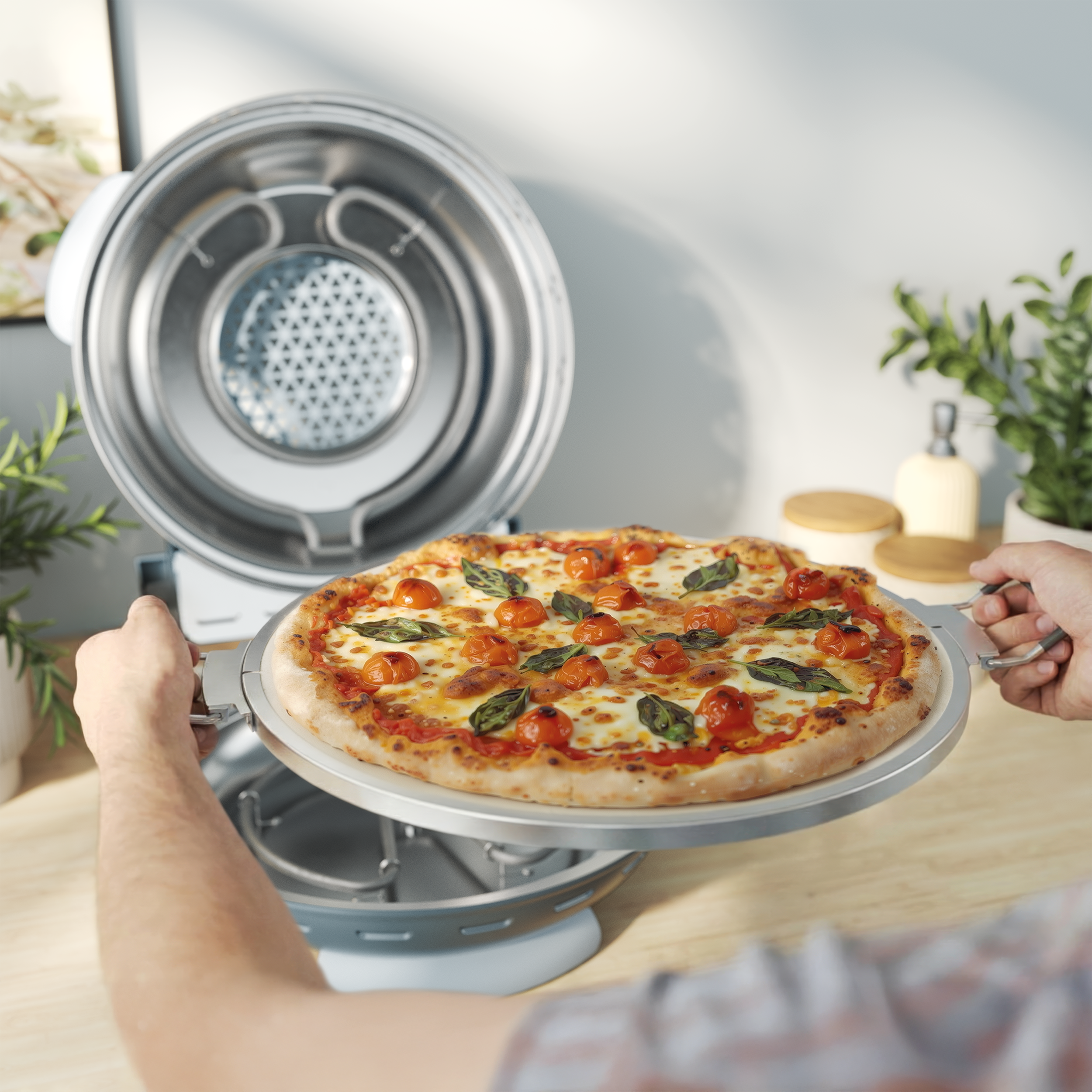 Egy személy frissen sült, paradicsomos és bazsalikomos pizzát tart egy sütőből.