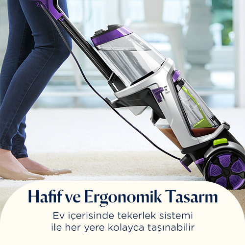 Bir kişi, halıyı mor ve gümüş renkli bir elektrikli süpürgeyle süpürüyor.