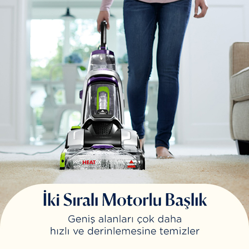 Bir kişi oturma odasında bej halıda halı temizleyici kullanıyor.