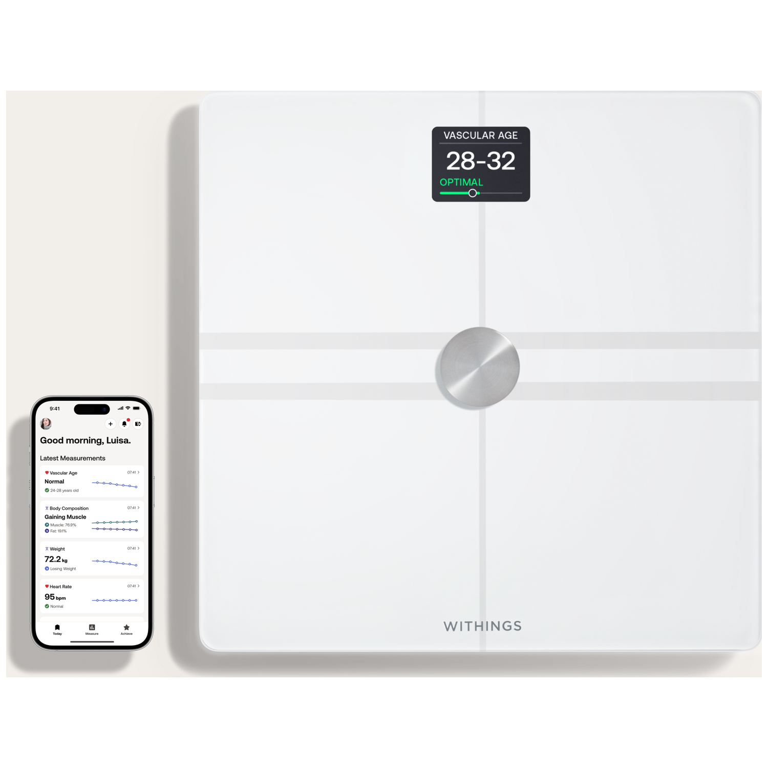 Een witte Withings smart scale toont 'Vasculaire Leeftijd 28-32 Optimaal'. Een telefoon toont gezondheidsgegevens.
