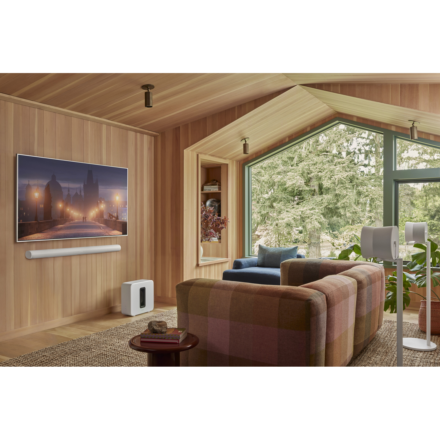 Een woonkamer met houten lambrisering, tv, bank en luidsprekers.