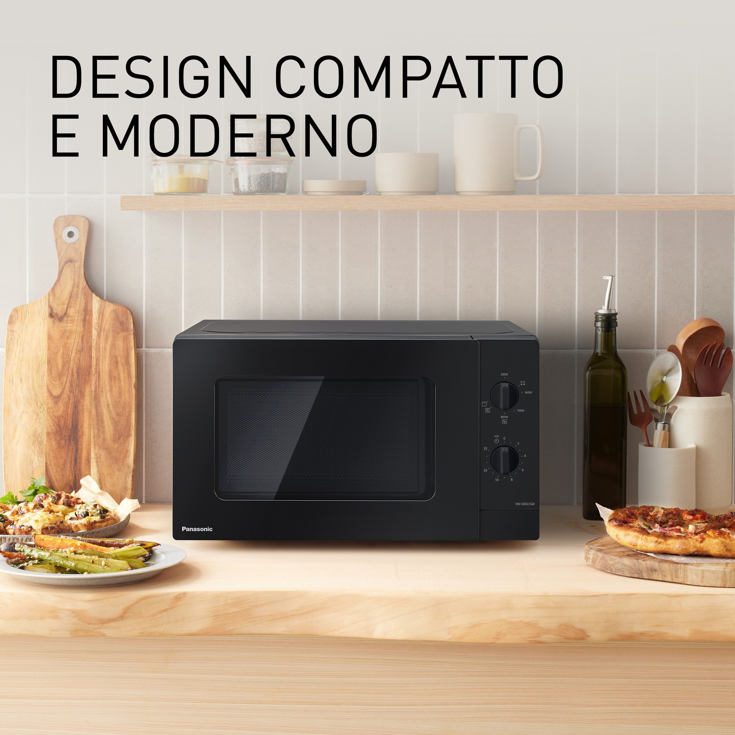 Forno a microonde nero su bancone in legno con cibo e utensili.