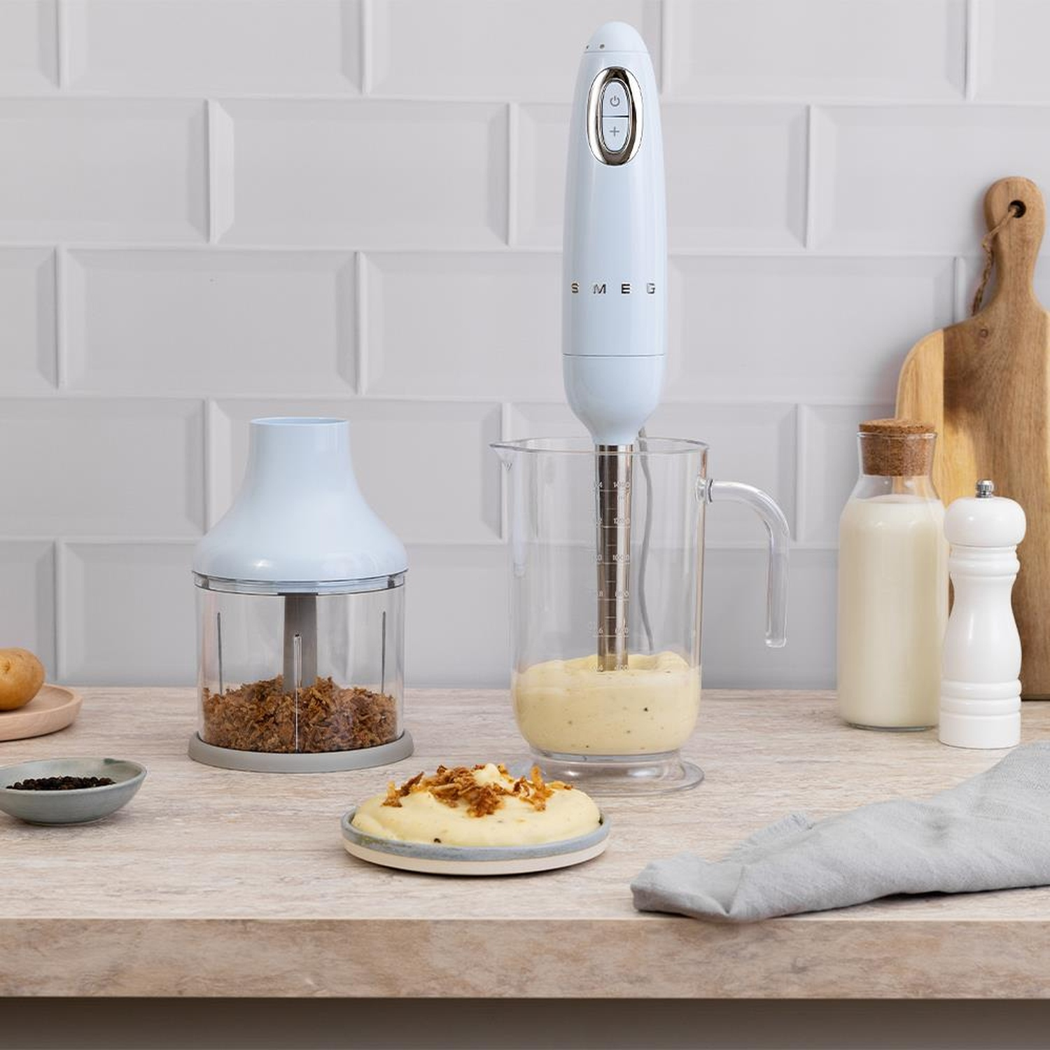 Frullatore a immersione Smeg azzurro in una caraffa con purè di patate e cipolle fritte.