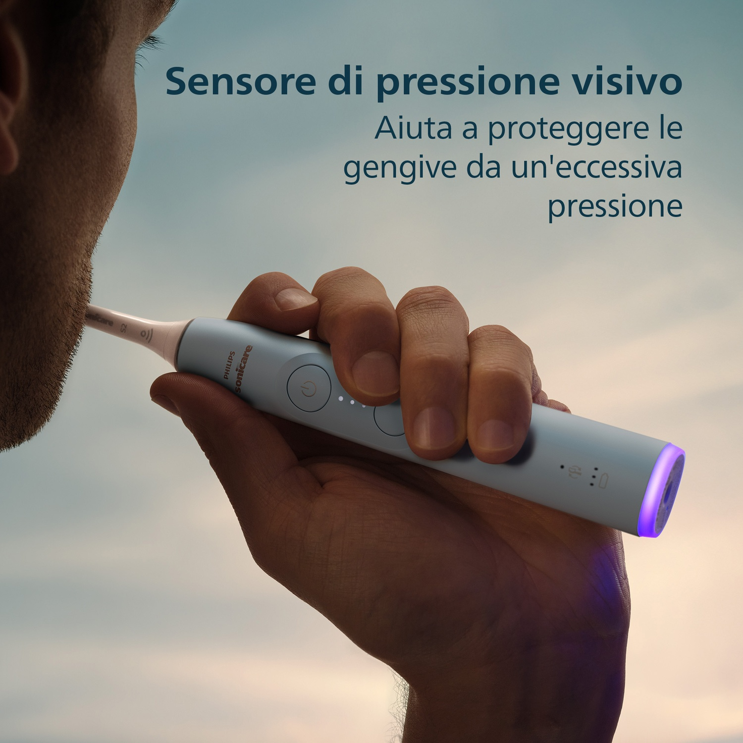 Un uomo tiene uno spazzolino Philips Sonicare con manico blu e luce viola.