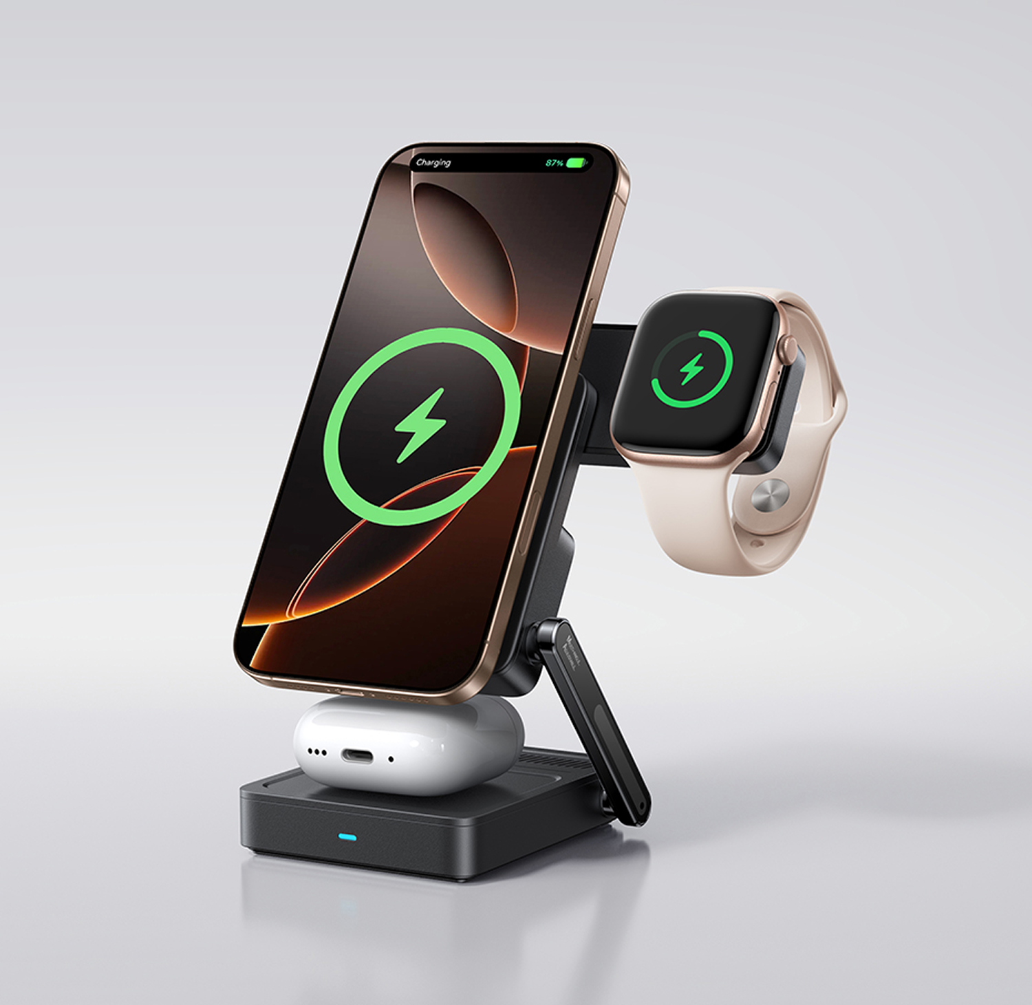 Un smartphone dorado, un reloj inteligente y auriculares se cargan en un soporte negro.