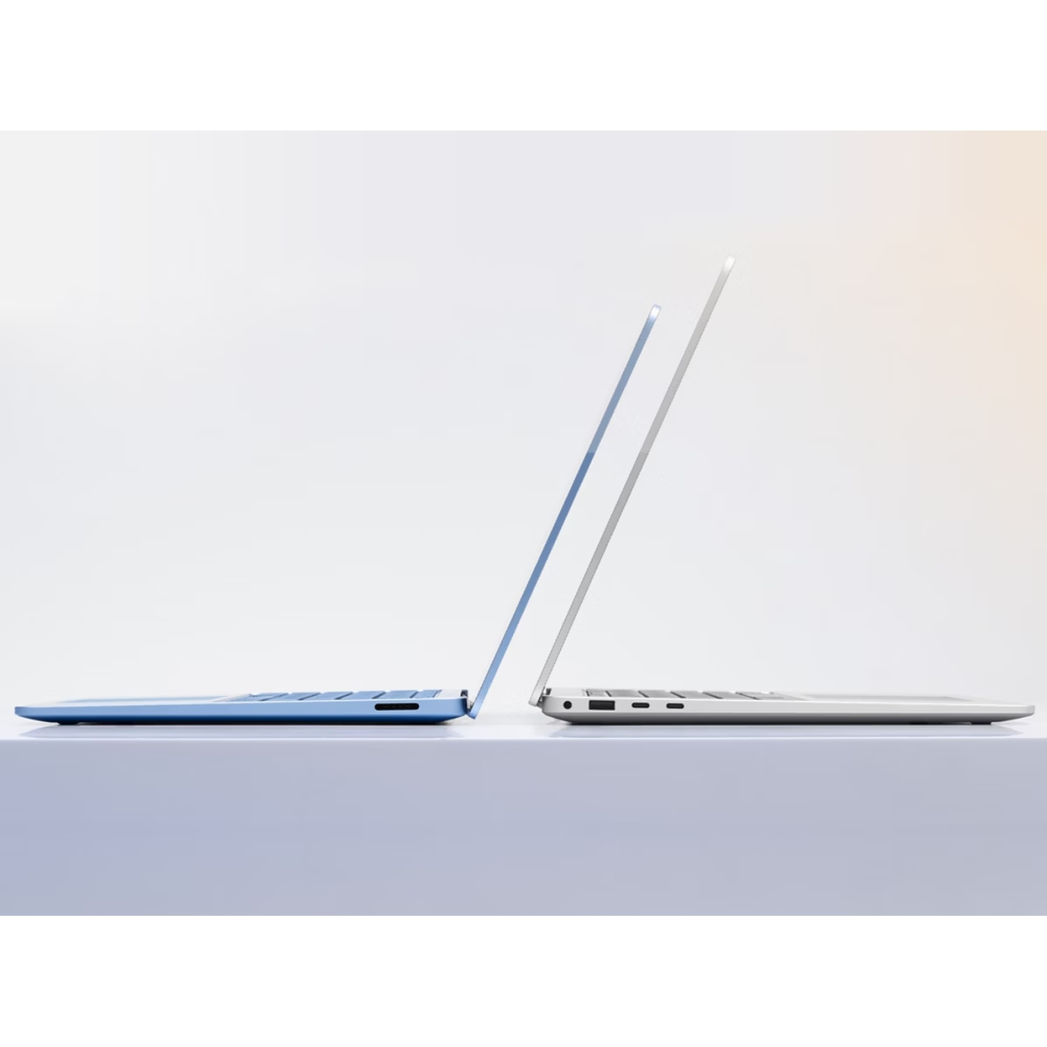 Deux ordinateurs portables, un bleu et un argenté, côte à côte sur une surface.