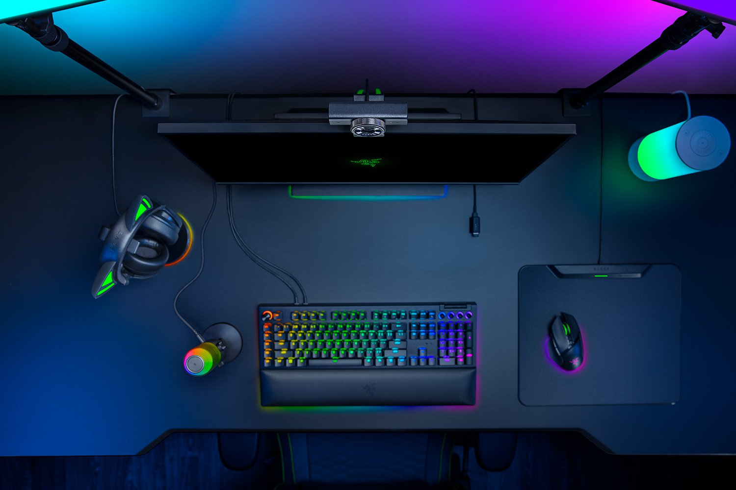 Una postazione da gaming con illuminazione RGB: monitor, tastiera, mouse, cuffie e microfono.