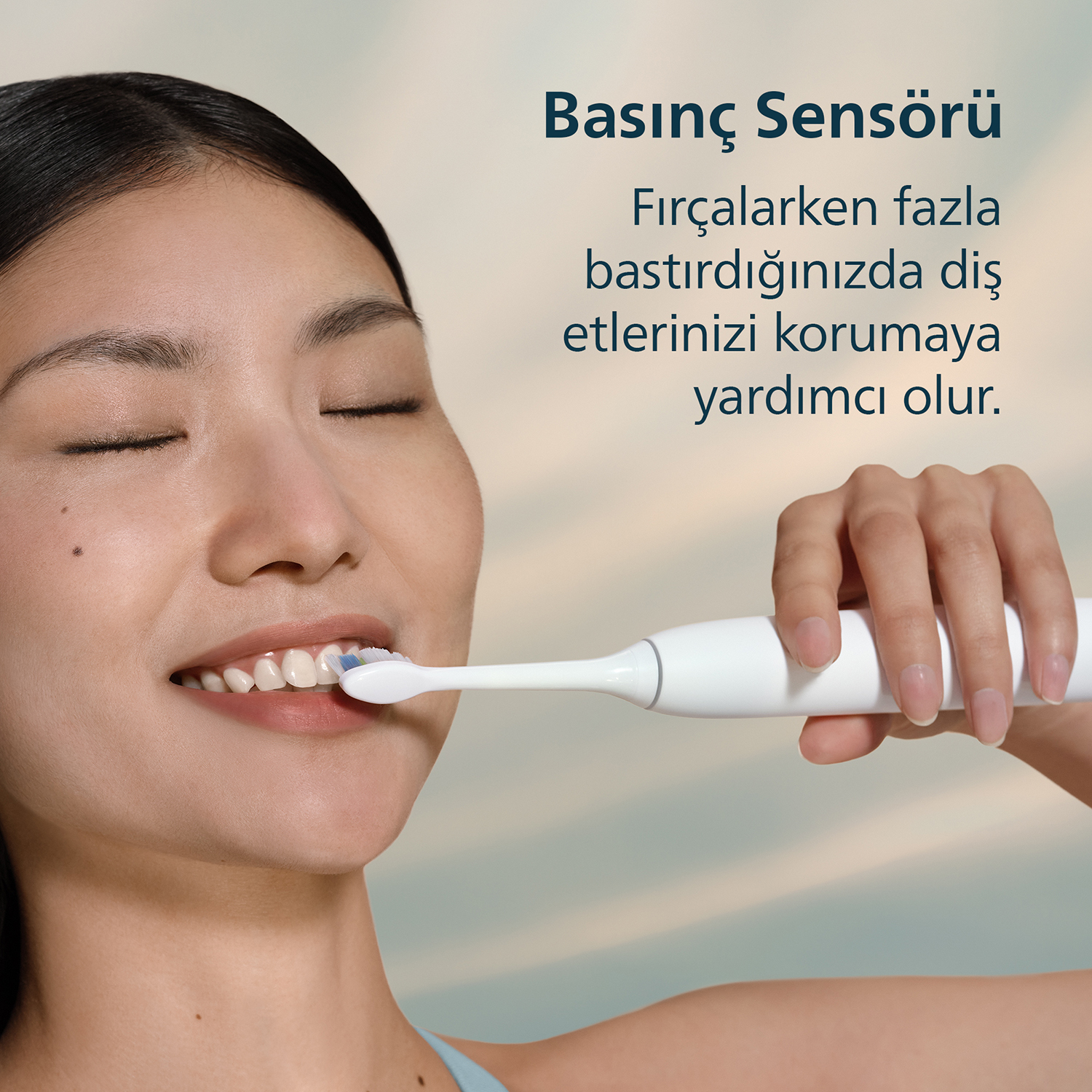 Bir kadın elektrikli diş fırçasıyla dişlerini fırçalıyor.