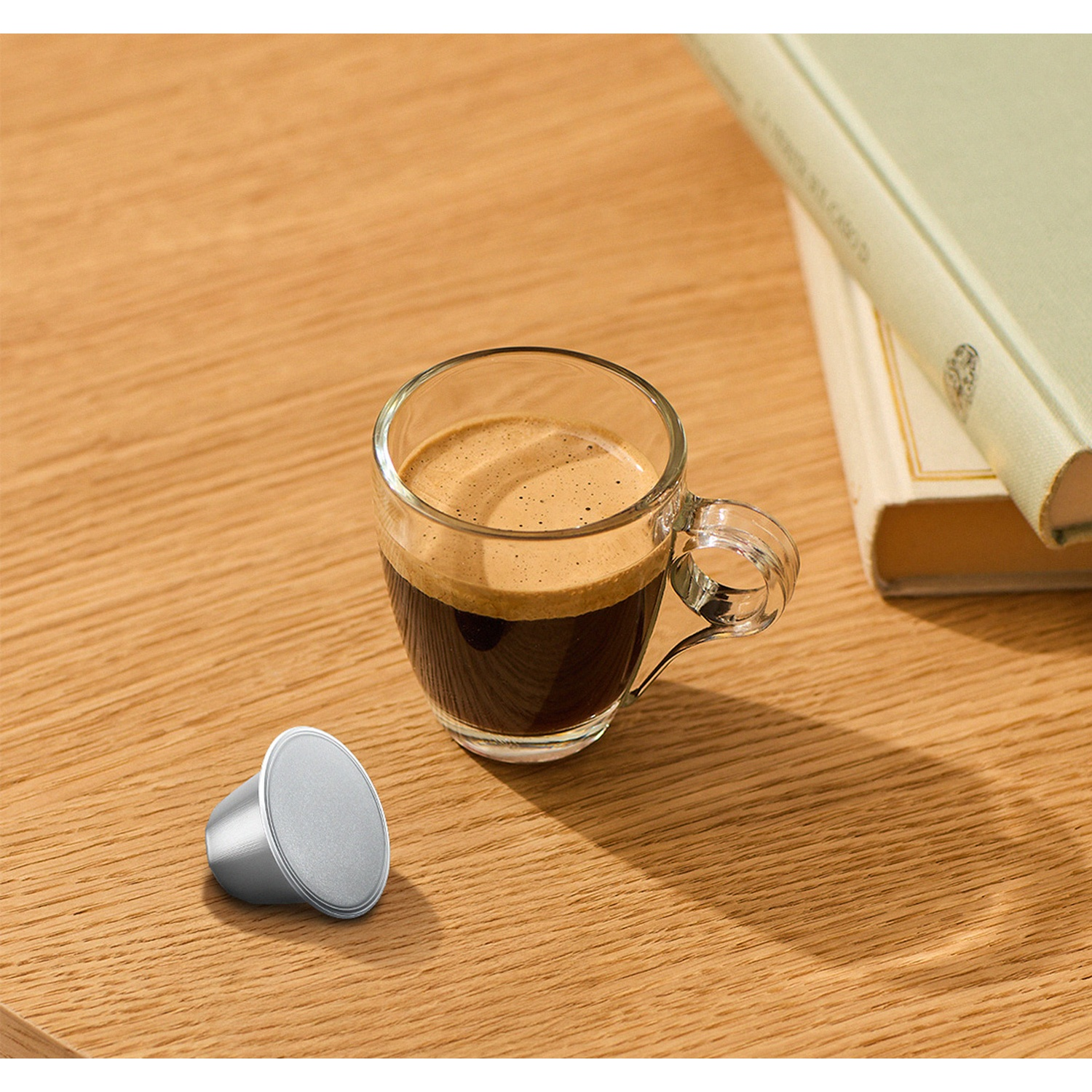 Una tazza di espresso e una capsula argentata su un tavolo di legno.