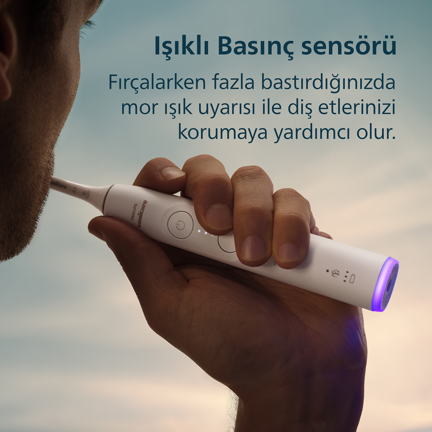 Mavi ışıklı beyaz elektrikli diş fırçası bir el tarafından tutuluyor.