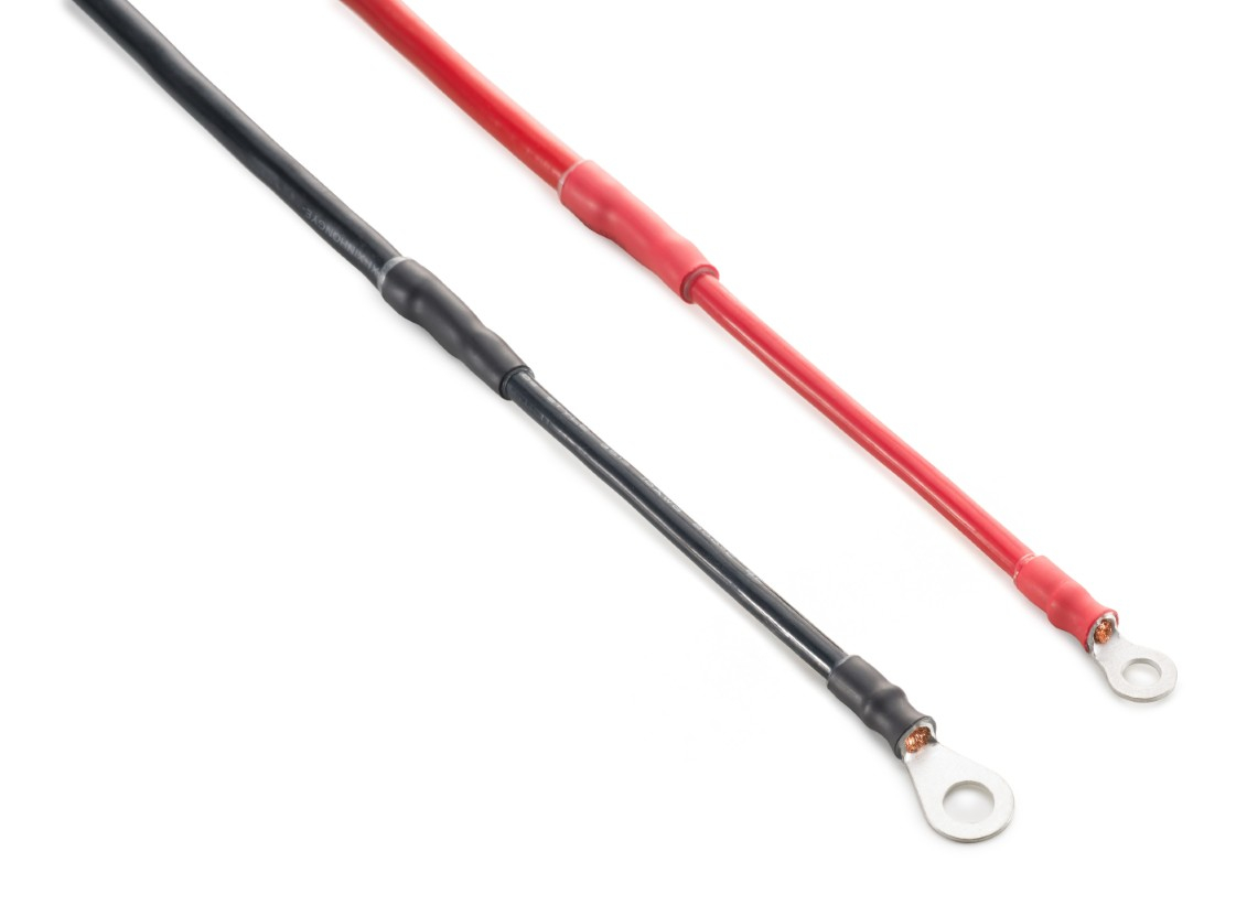 Dwa kable, czerwony i czarny, z konektorami pierścieniowymi, na białym tle.