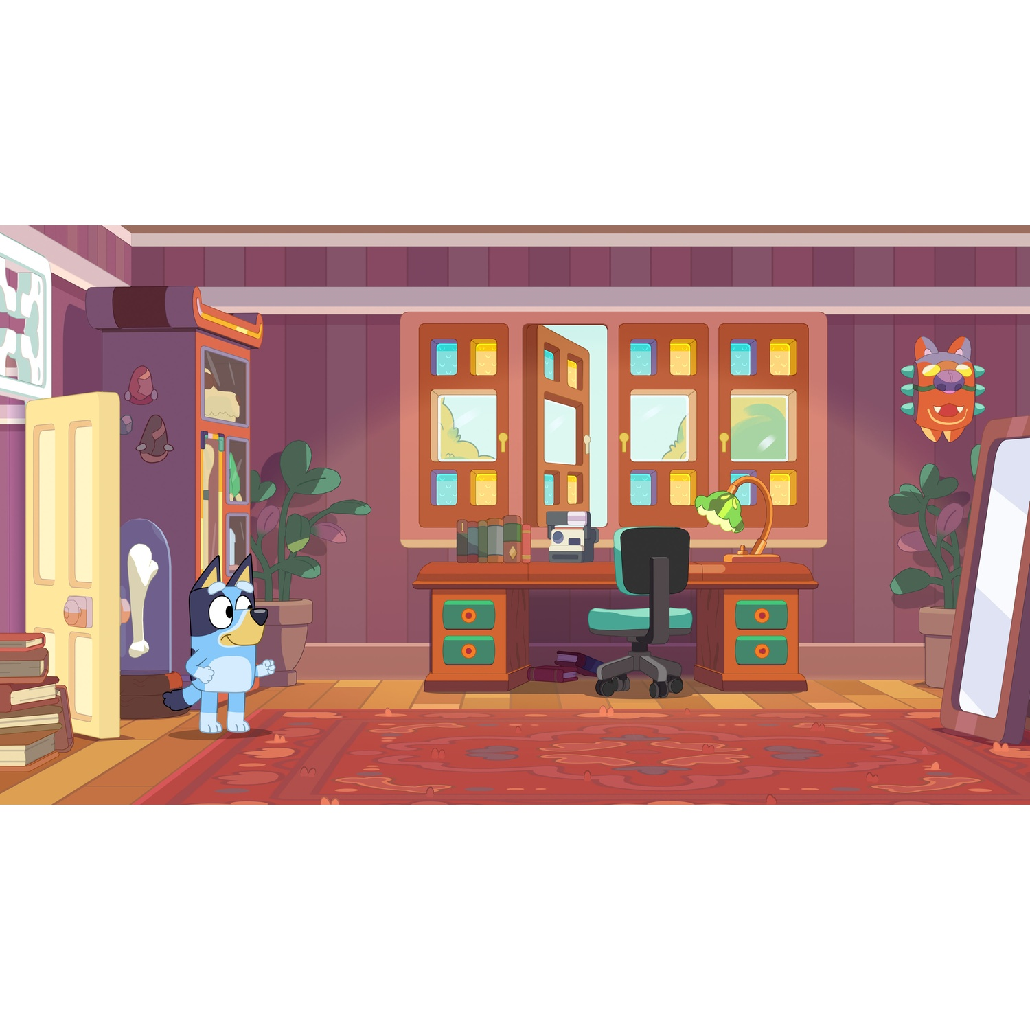 A blue dog stands on a rug in front of a desk with a chair.