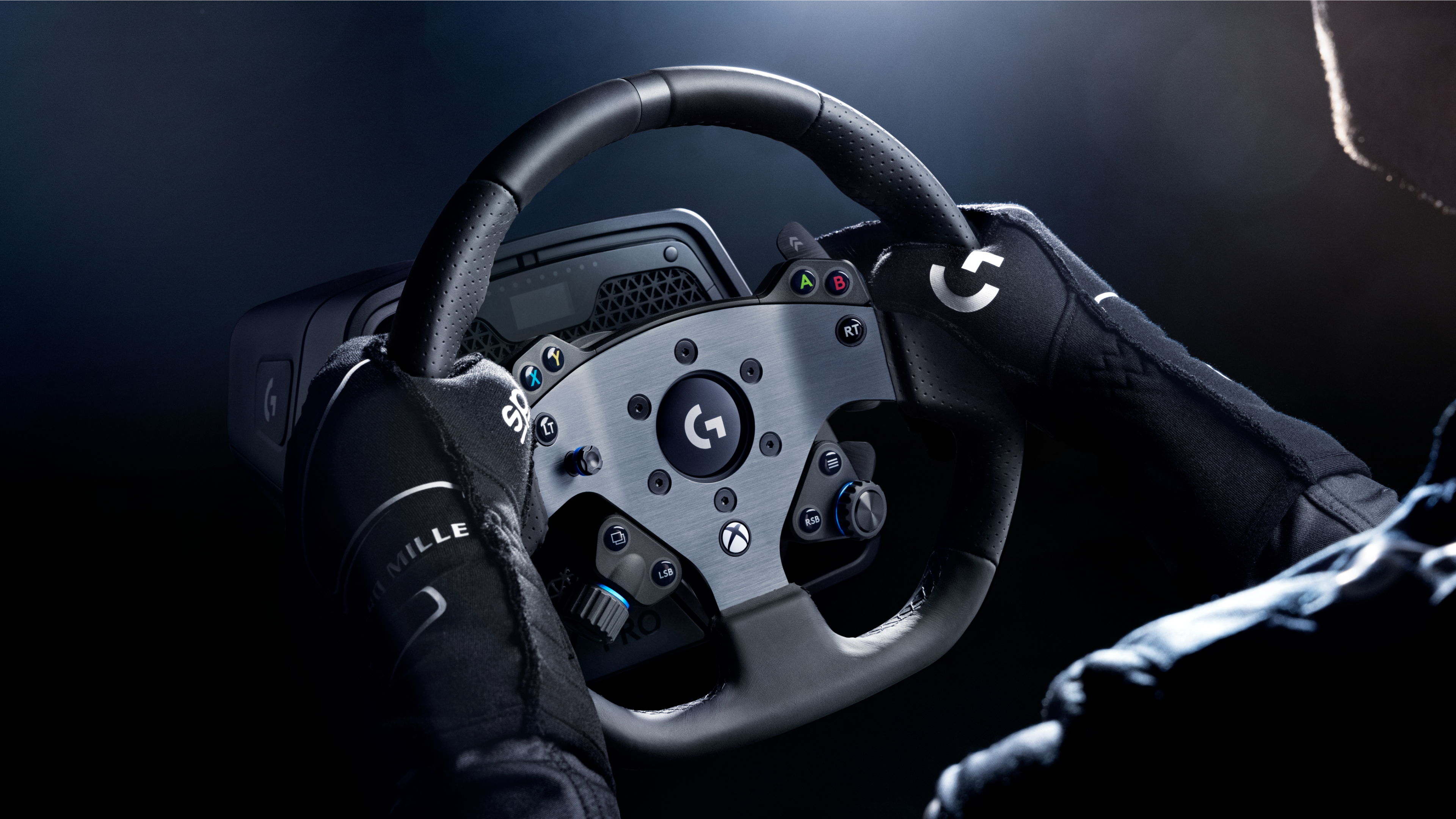 Personne portant des gants tient un volant Logitech sur fond sombre.