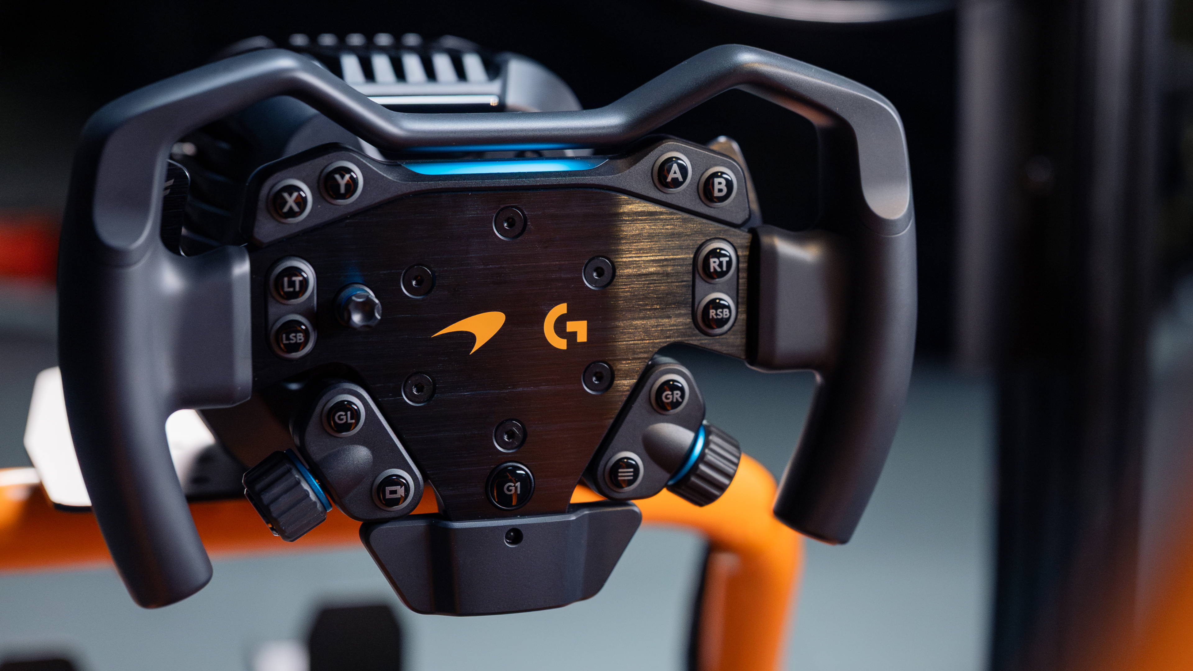 Un volant de course noir avec logos orange et accents bleus.