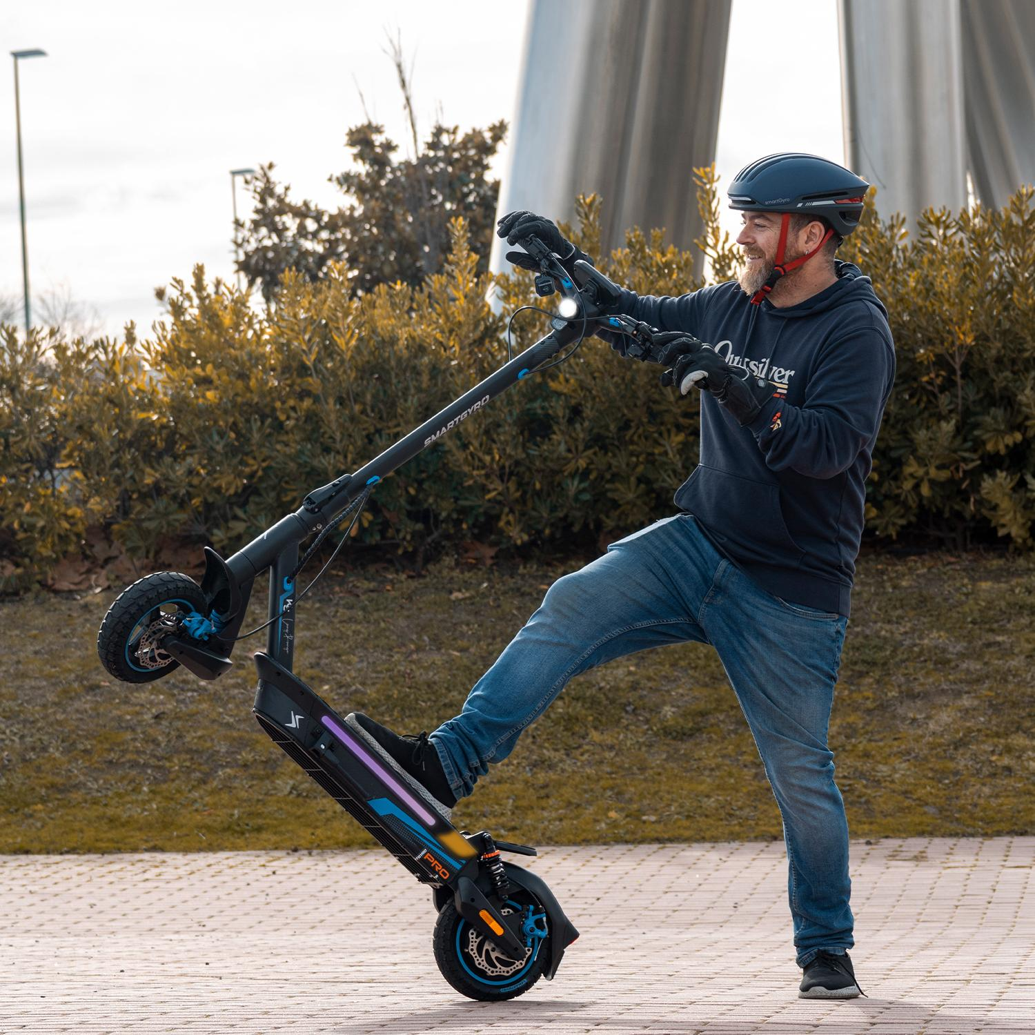 Hombre con casco se equilibra en patinete eléctrico.
