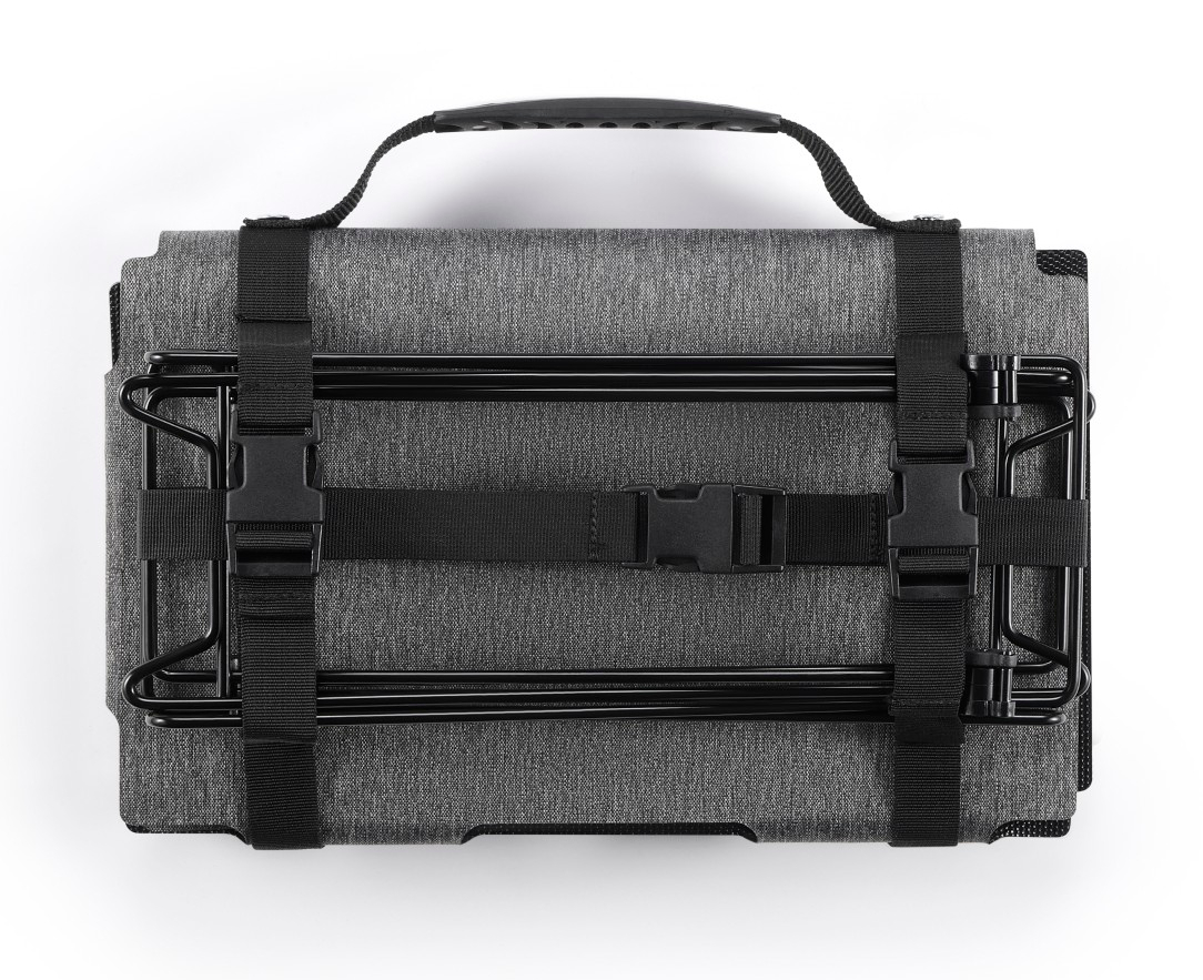 Szara, złożona torba z czarnym uchwytem i paskami.