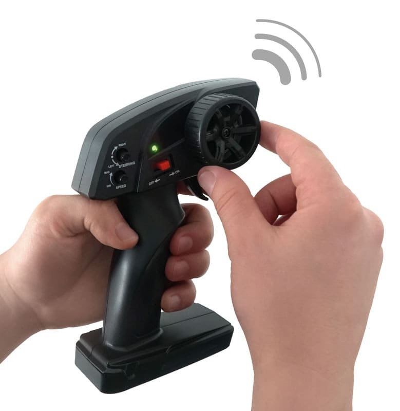 Dłonie obsługują czarny pilot do samochodu RC z kierownicą i przyciskami.
