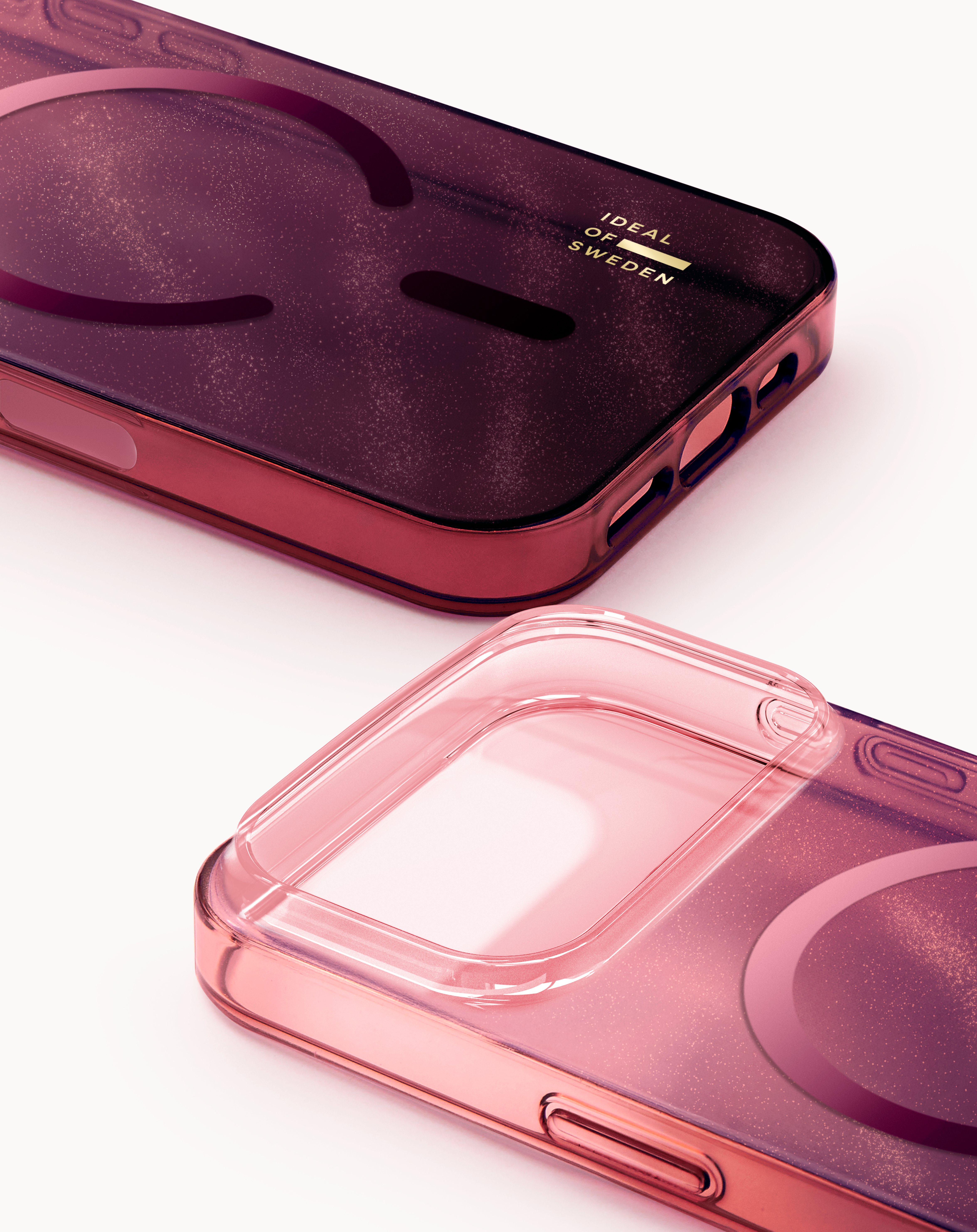 Zwei rosa iPhone-Hüllen liegen nebeneinander. Eine ist transparent, die andere dunkelrot mit Glitzer.