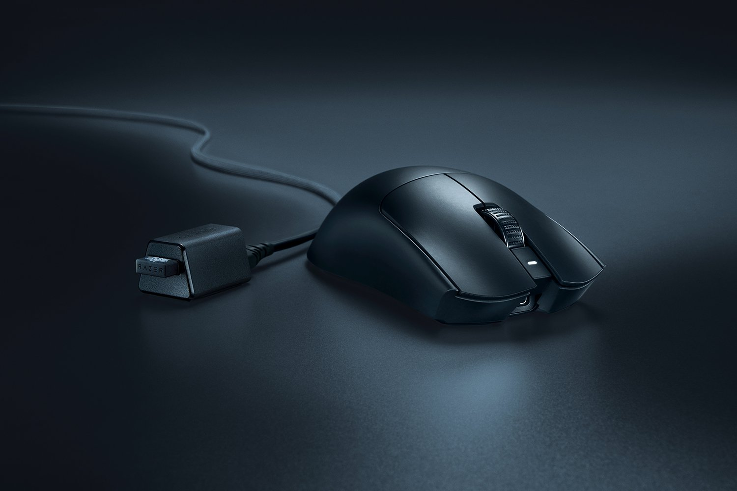 Mouse gaming Razer nero con cavo e dongle su sfondo scuro.