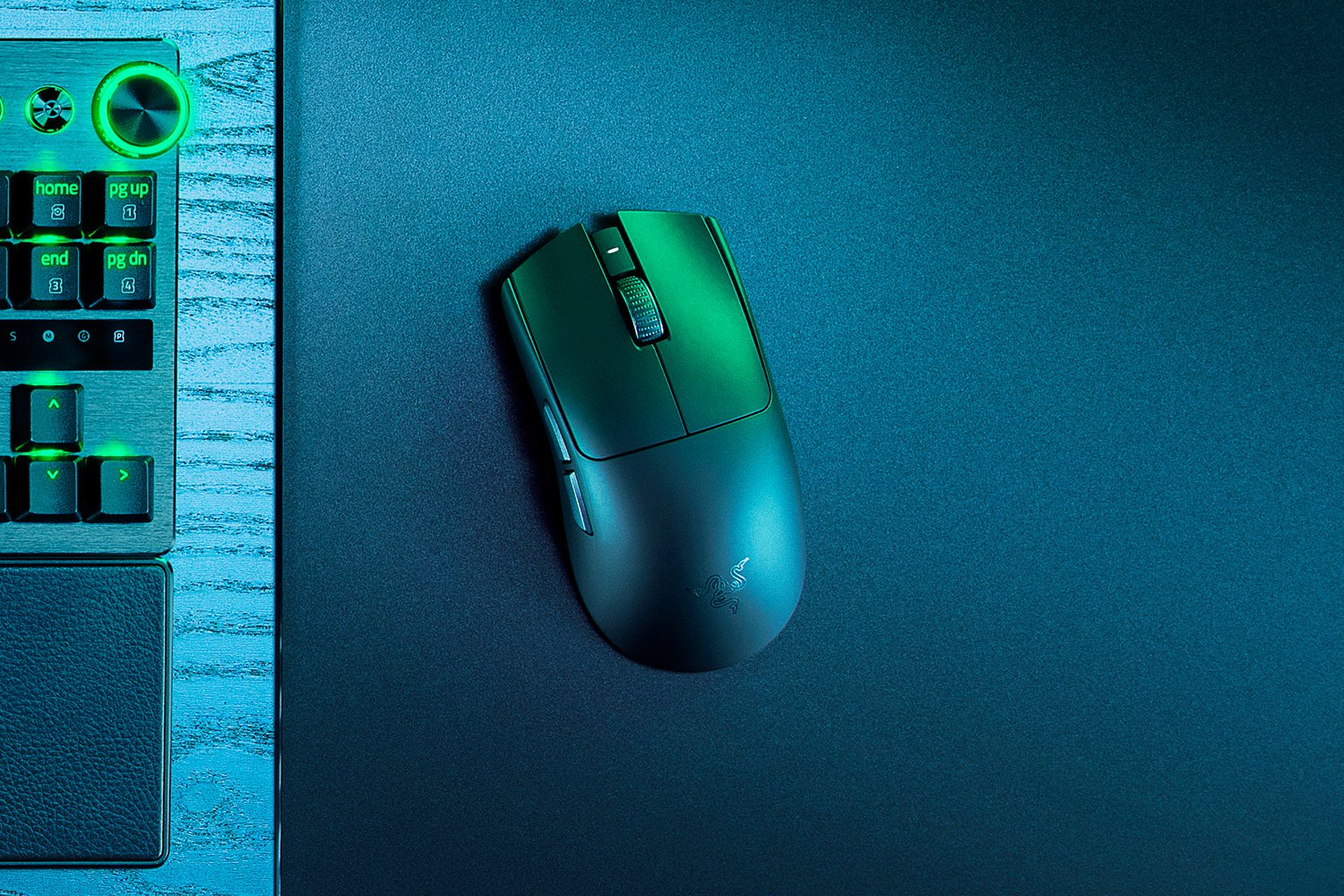 Un mouse da gaming verde su un tappetino nero accanto a una tastiera.