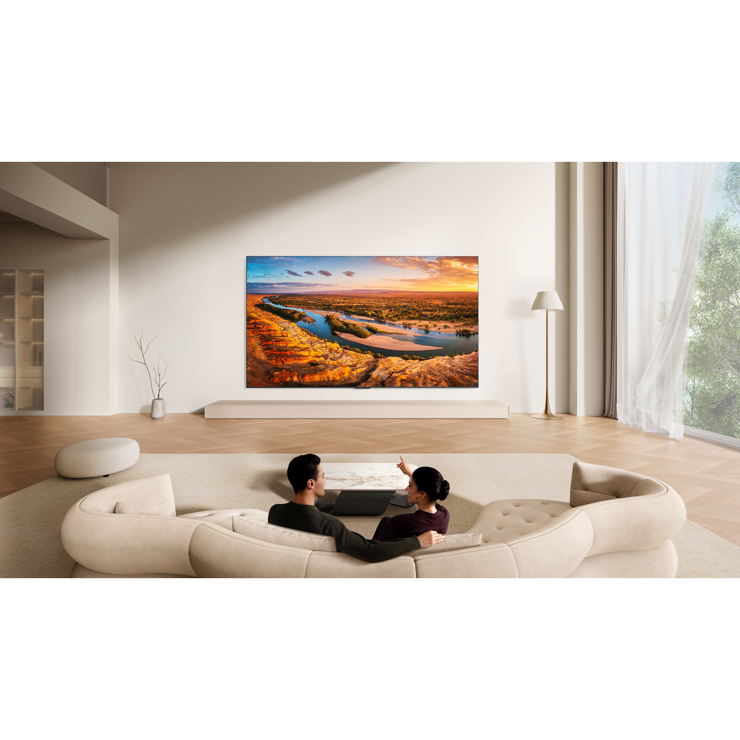Een stel zit op een bank en kijkt naar een grote tv met een landschap erop.