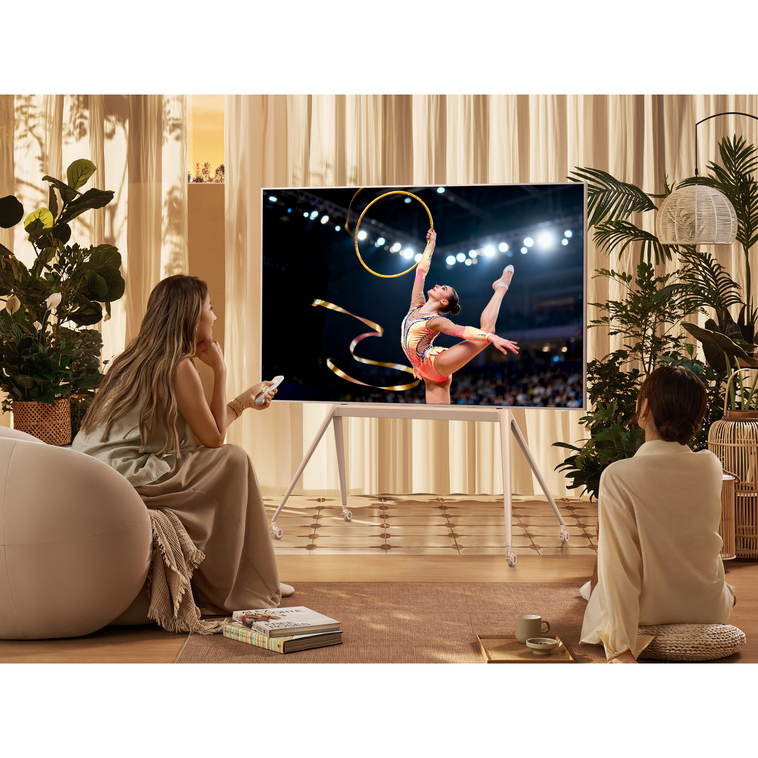 Twee vrouwen kijken naar een gymnastiekcompetitie op een tv-scherm.