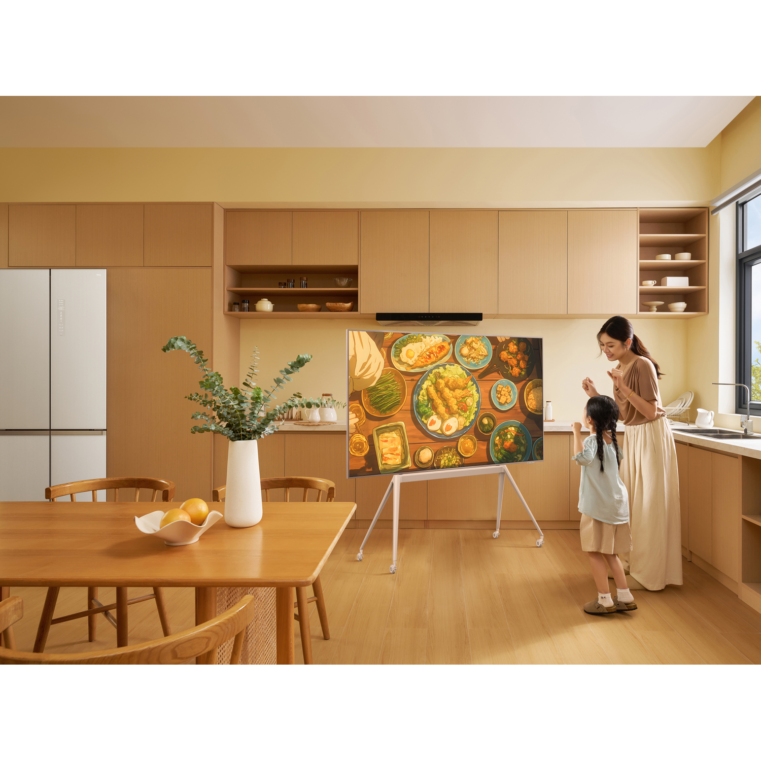 Moeder en kind kijken naar een tv met voedselafbeeldingen in een moderne keuken.