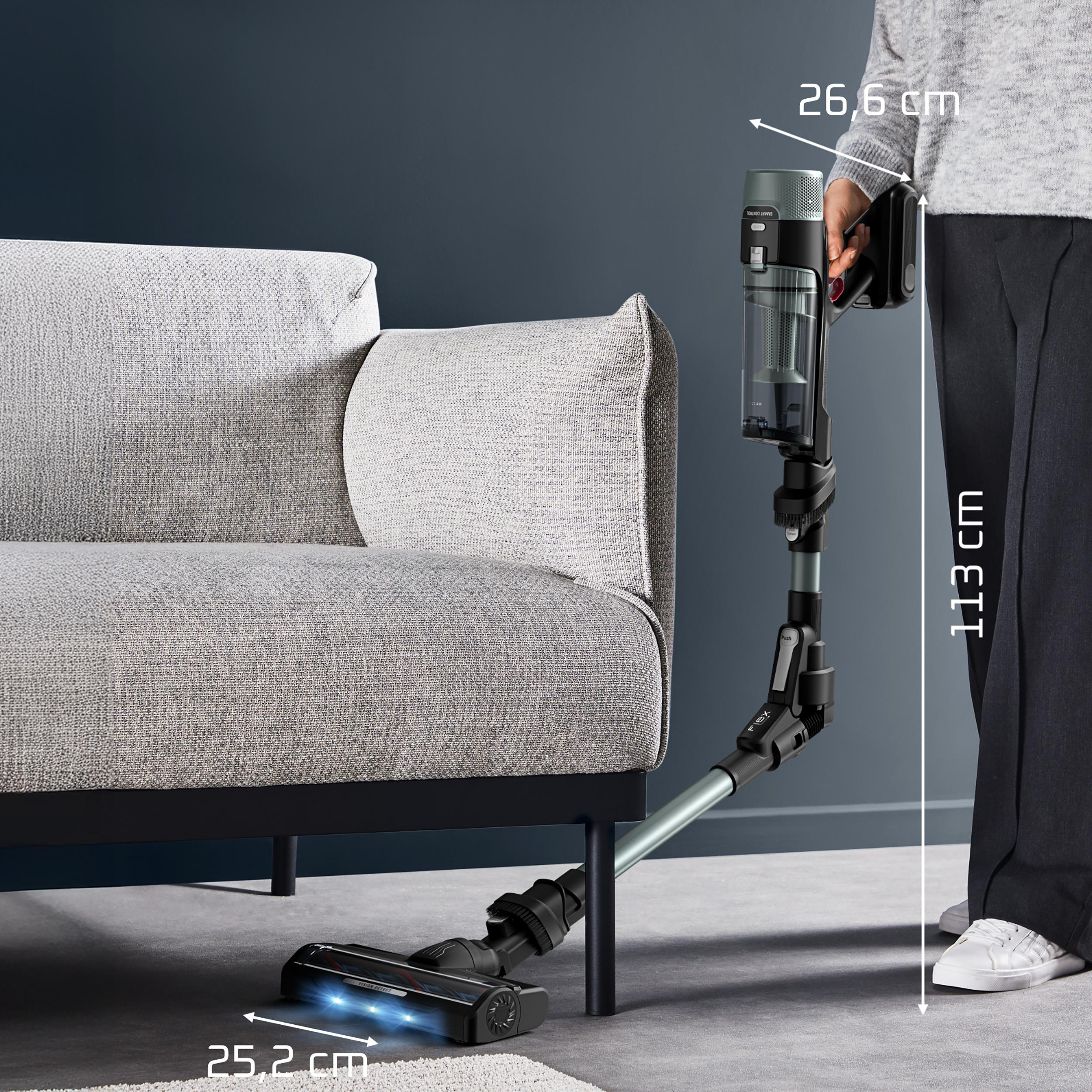 Ein Handstaubsauger wird neben einem grauen Sofa gezeigt. Maße sind angegeben.