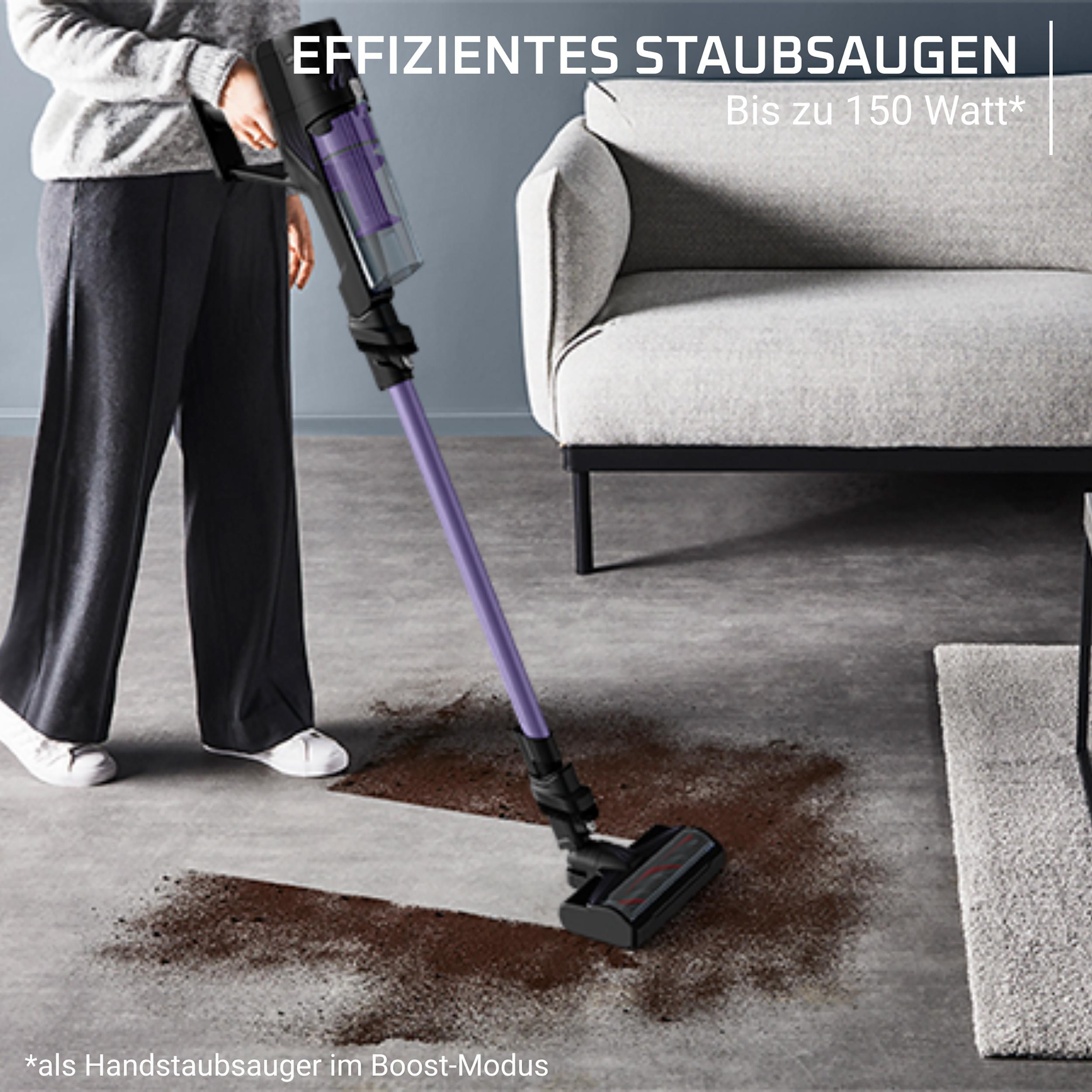 Eine Person saugt mit einem lila Handstaubsauger Schmutz auf.