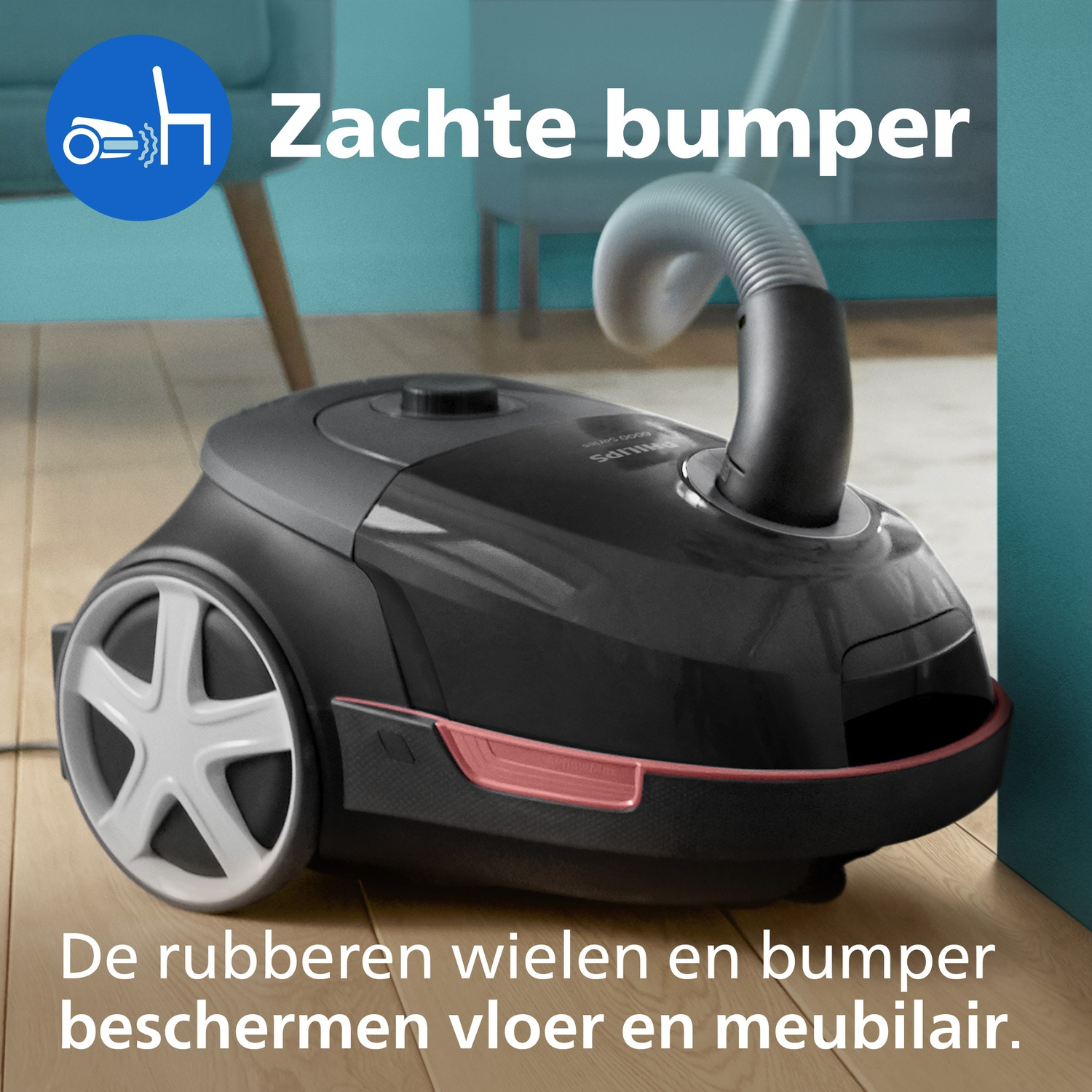 Black vacuum cleaner with hose and wheels on a wooden floor.