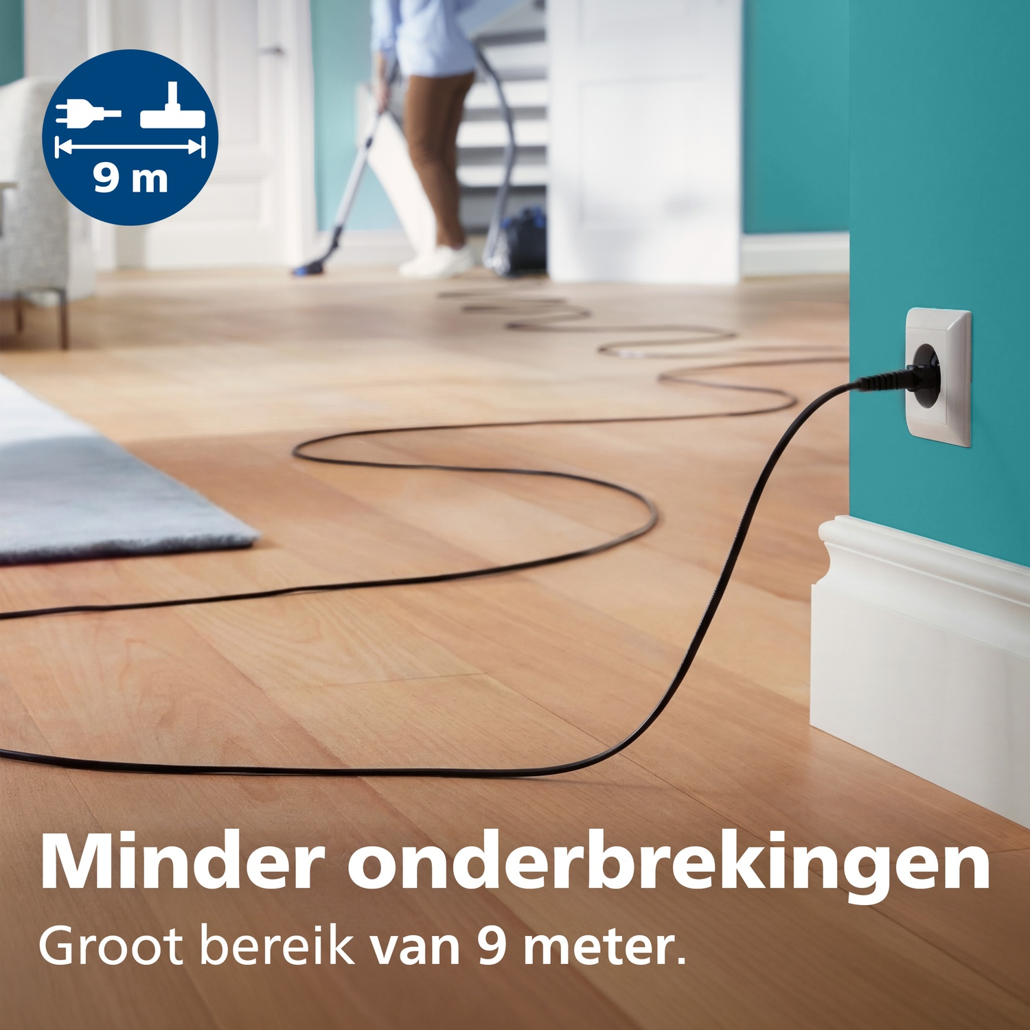 A vacuum cleaner cord stretches across a wooden floor to an electrical outlet.