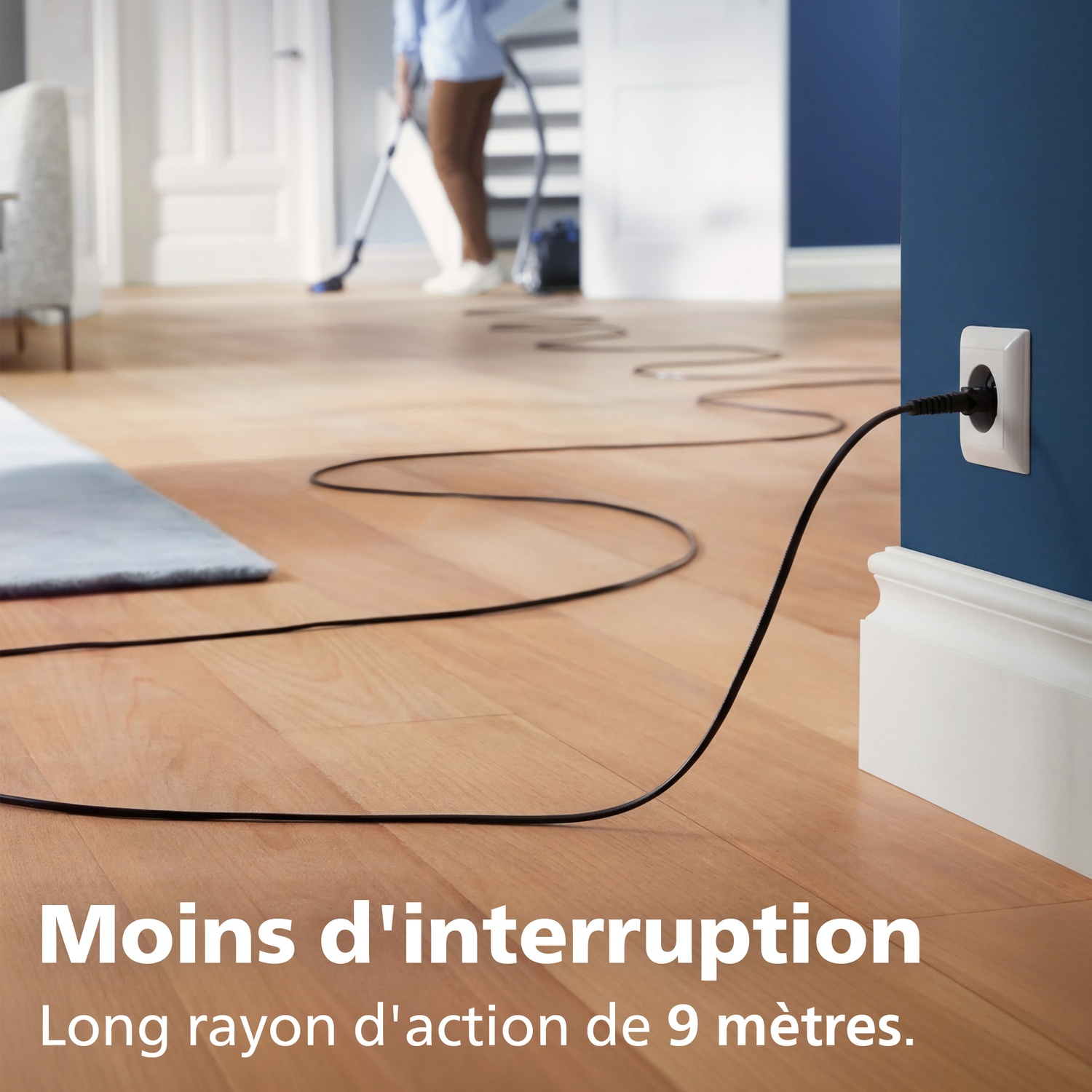 Un cordon noir part d'une prise sur un plancher en bois.