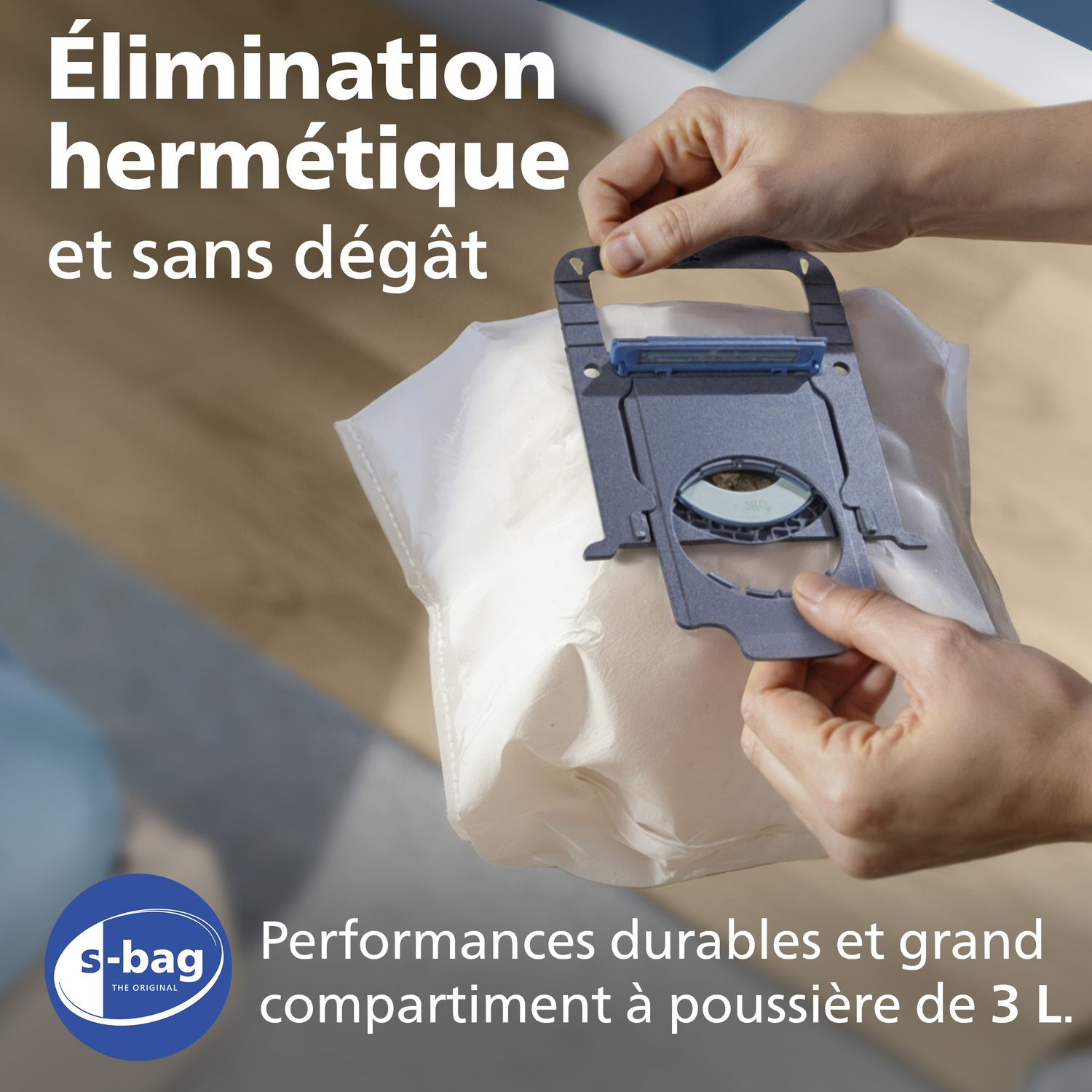 Une main tient un support de sac à poussière sur un sac blanc. Logo S-bag.