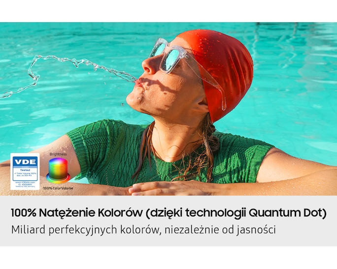 Kobieta w czerwonym czepku rozpryskuje wodę w basenie, ubrana na zielono.