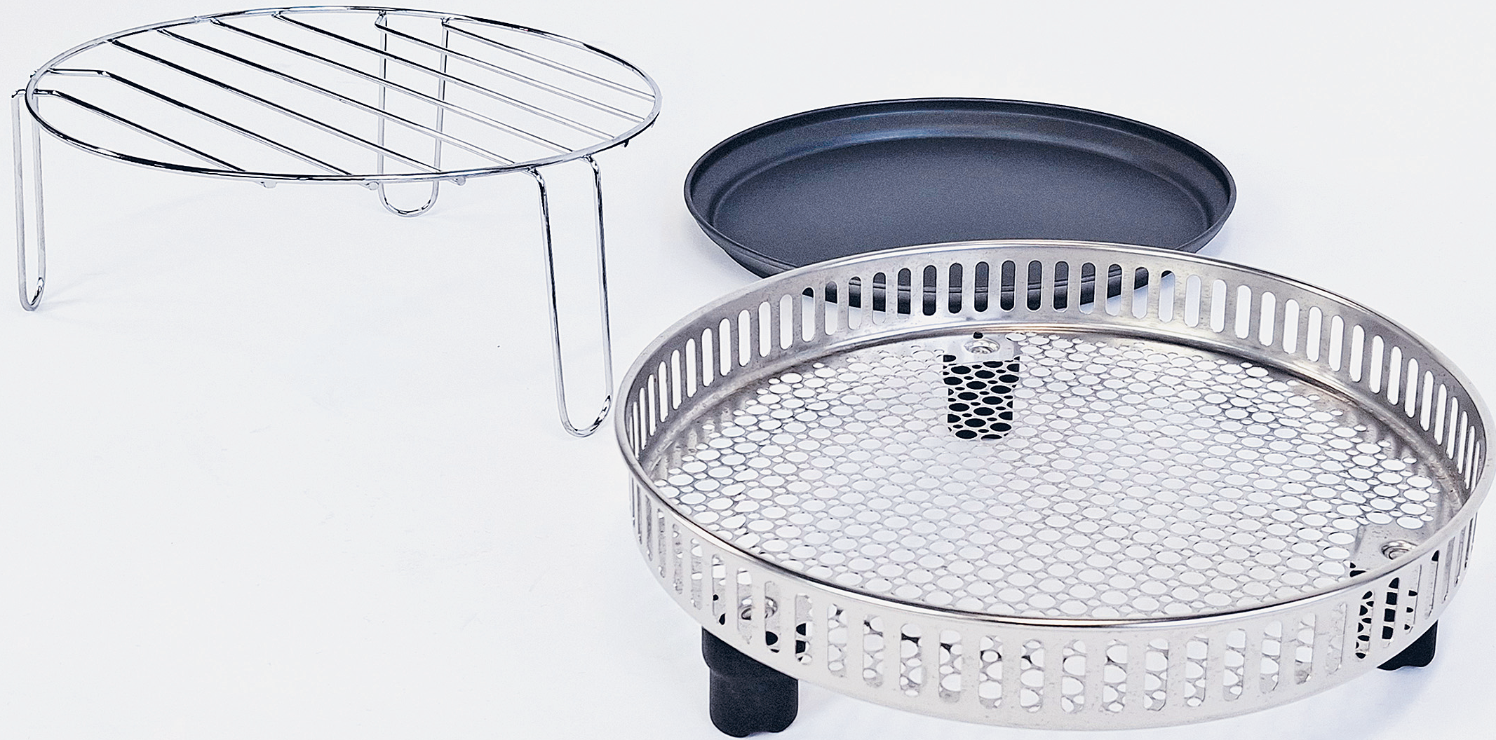 Une grille argentée, une poêle noire et un panier rond en métal sur fond blanc.