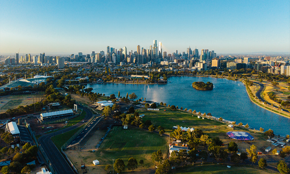 Widok z lotu ptaka na panoramę miasta, niebieskie jezioro i tor wyścigowy z zielonymi polami.