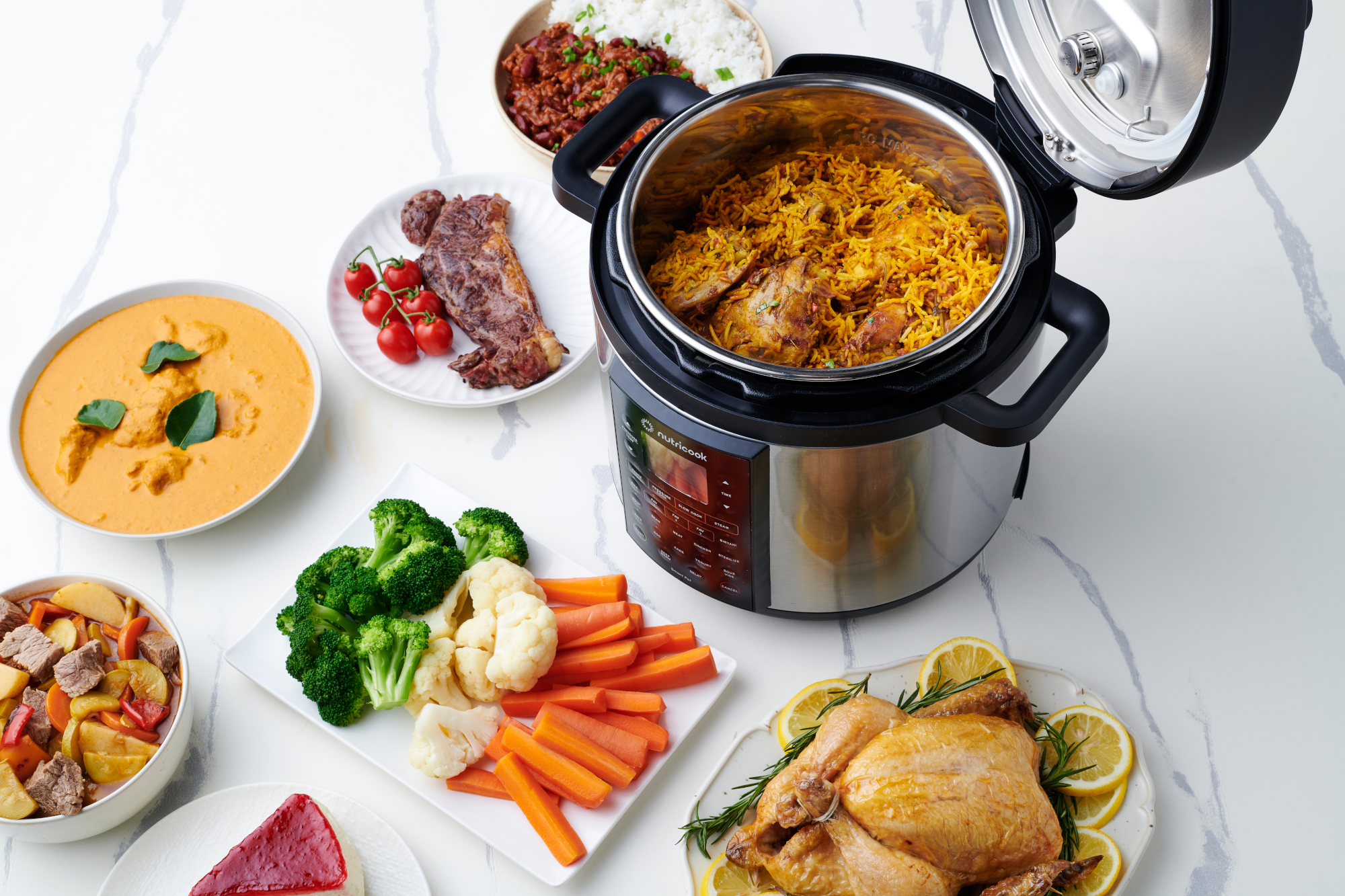 Egy multifunkciós főző edény rizsételekkel, sült csirkével, marhahússal, zöldségekkel és tortával.