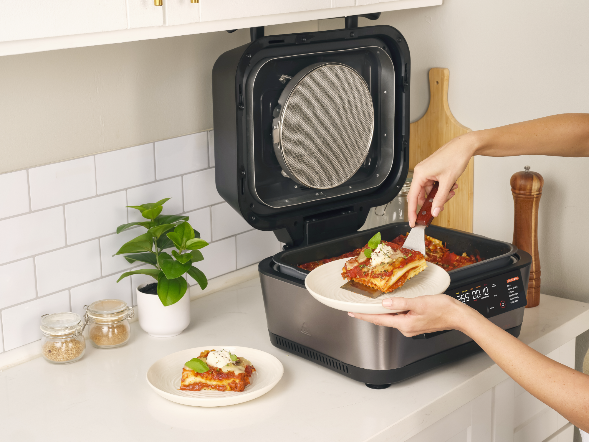 Egy személy lasagnét szolgál fel egy nyitott főzőedényből egy tányérra.