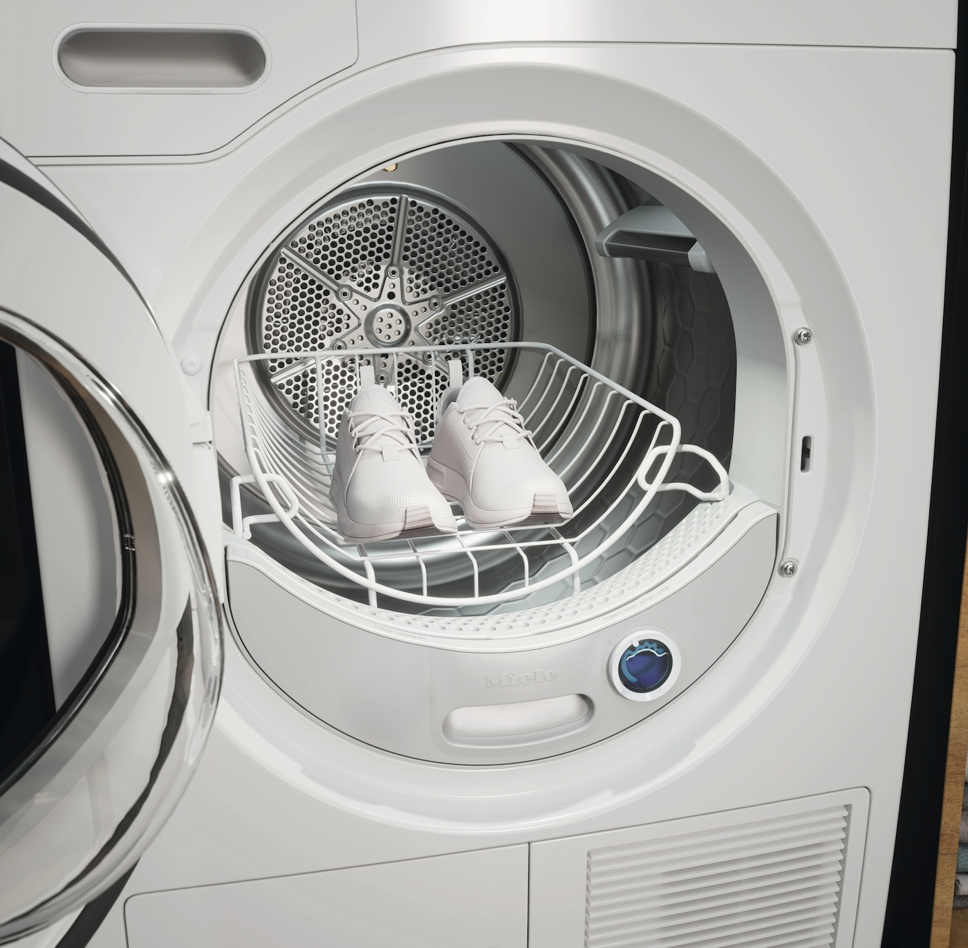 Zwei weiße Turnschuhe ruhen in einem Wäschetrockner auf einem Drahtgestell.