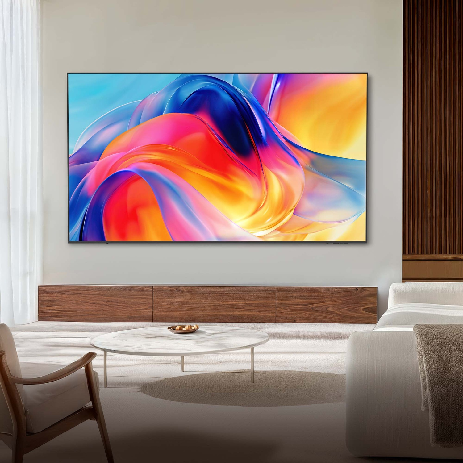 Una grande TV mostra forme astratte colorate. Un tavolino da caffè davanti.