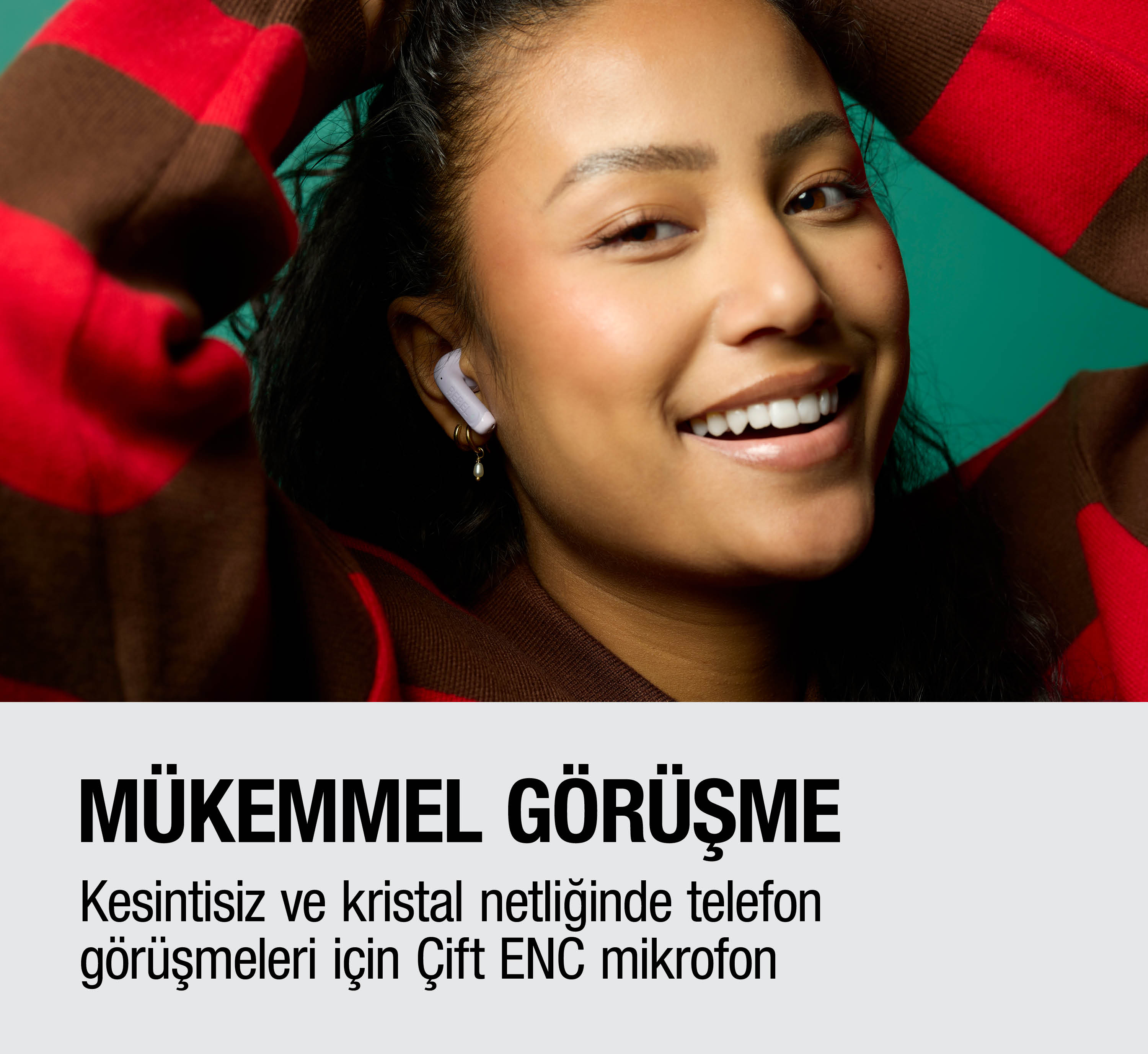 Gülümseyen kadın kulaklıkla, kırmızı-kahverengi çizgili kazak, yeşil arka plan.